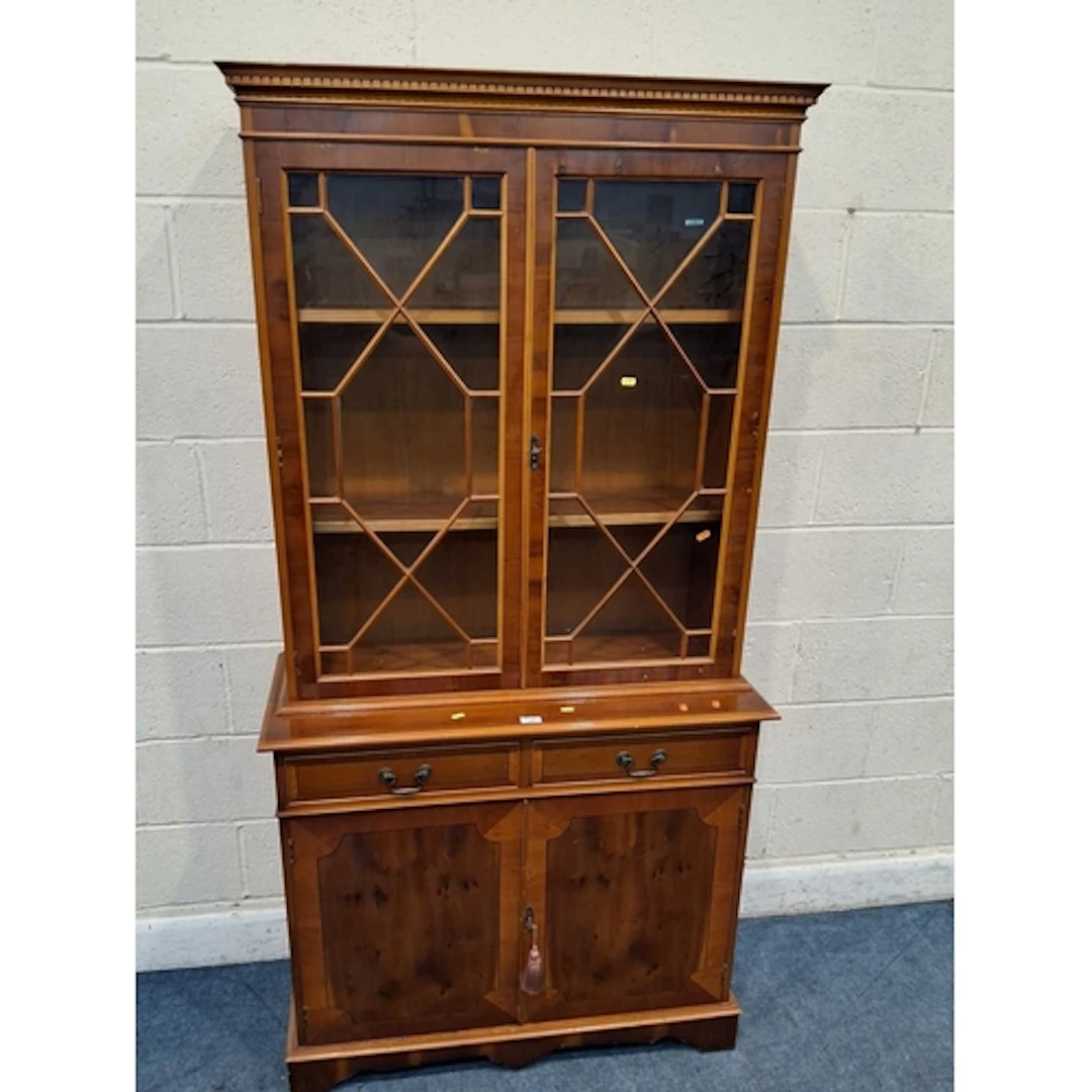 A REPRODUCTION YEW WOOD BOOKCASE, the double glass doors enc...