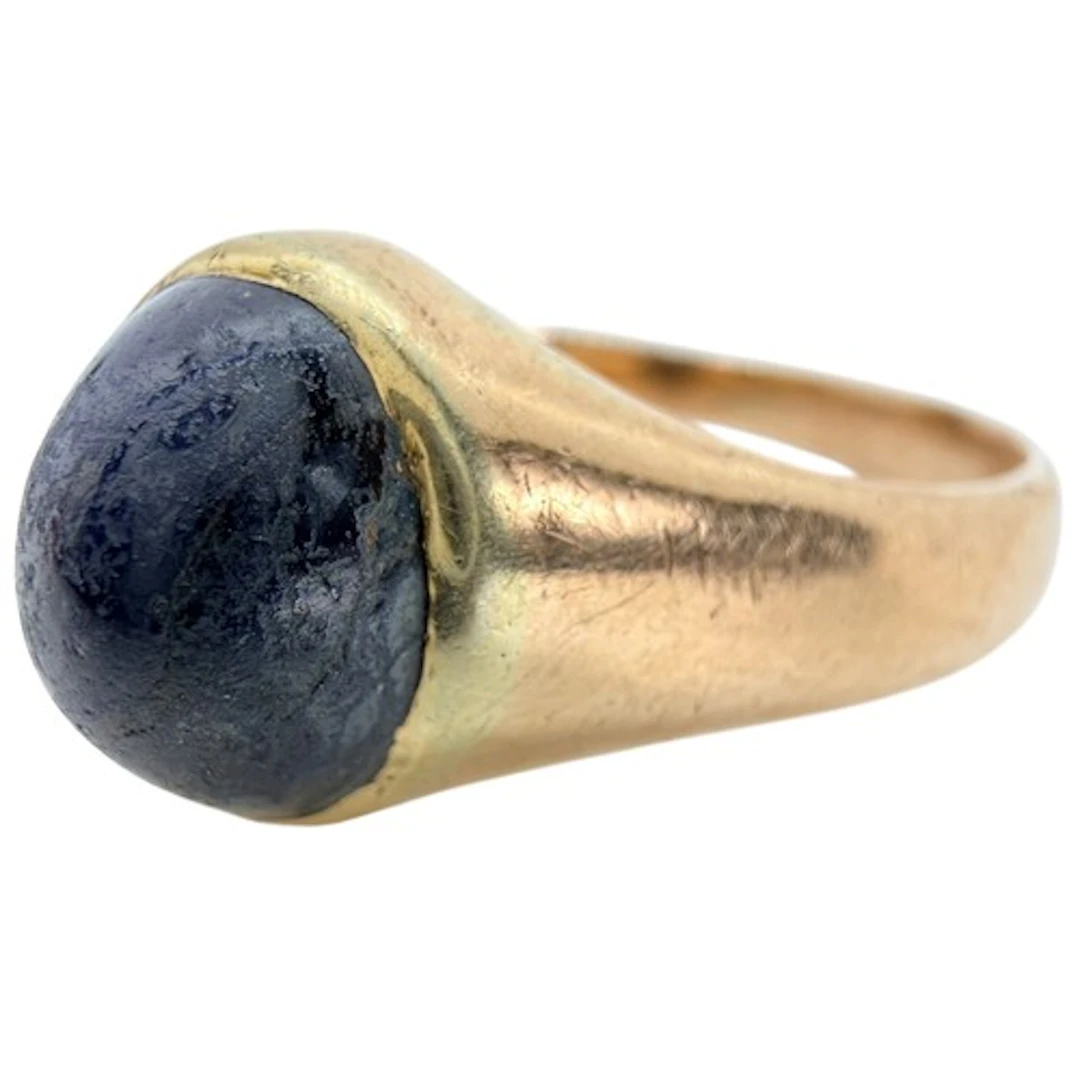 An antique unmarked gold ring set with a cabochon sapphire l...