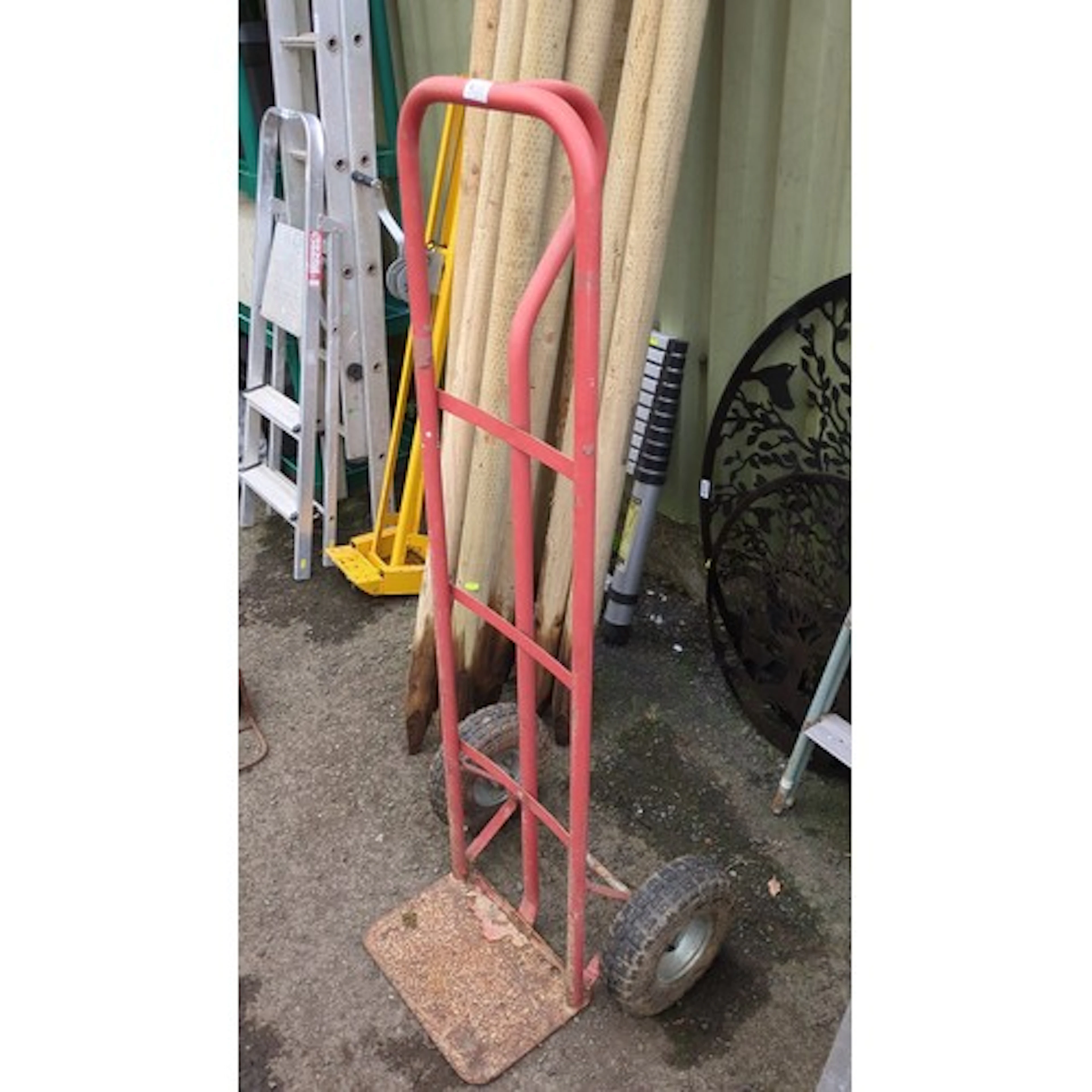 Two-wheeled steel sack truck, the tubular red-painted frame ...