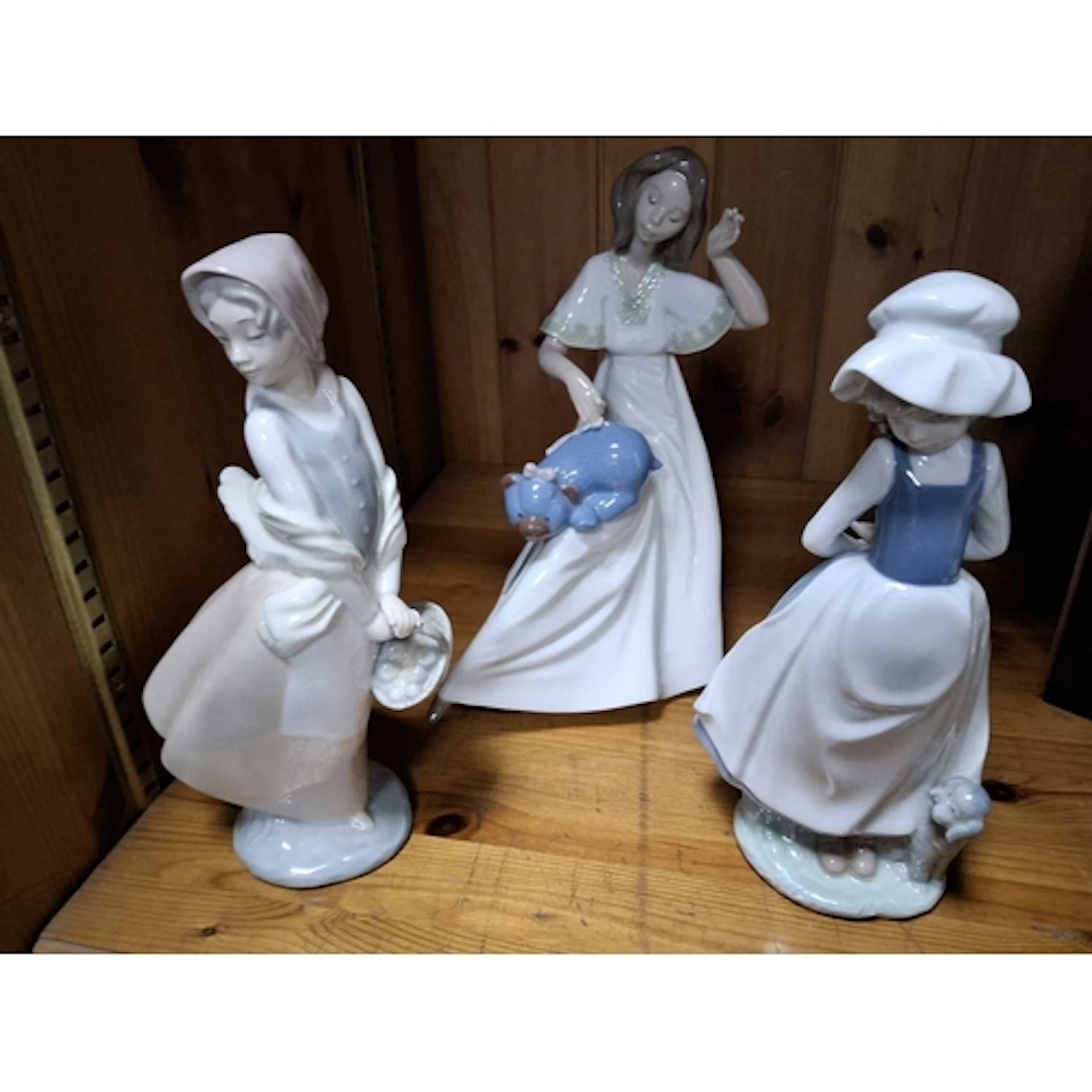 THREE NAO FIGURES, comprising a woman with a teddy bear, a g...