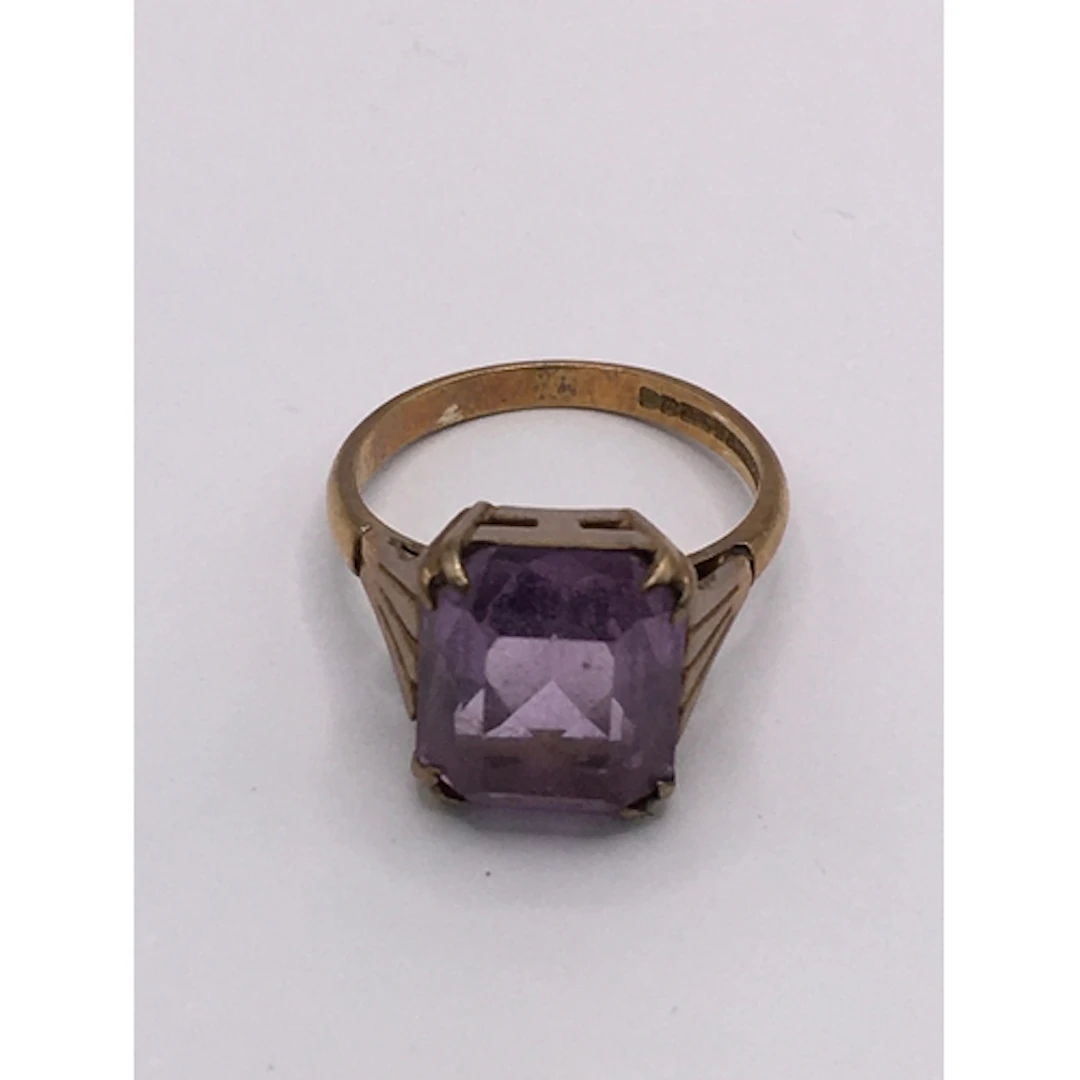 A 9ct gold ring set with an amethyst coloured square stone. ...