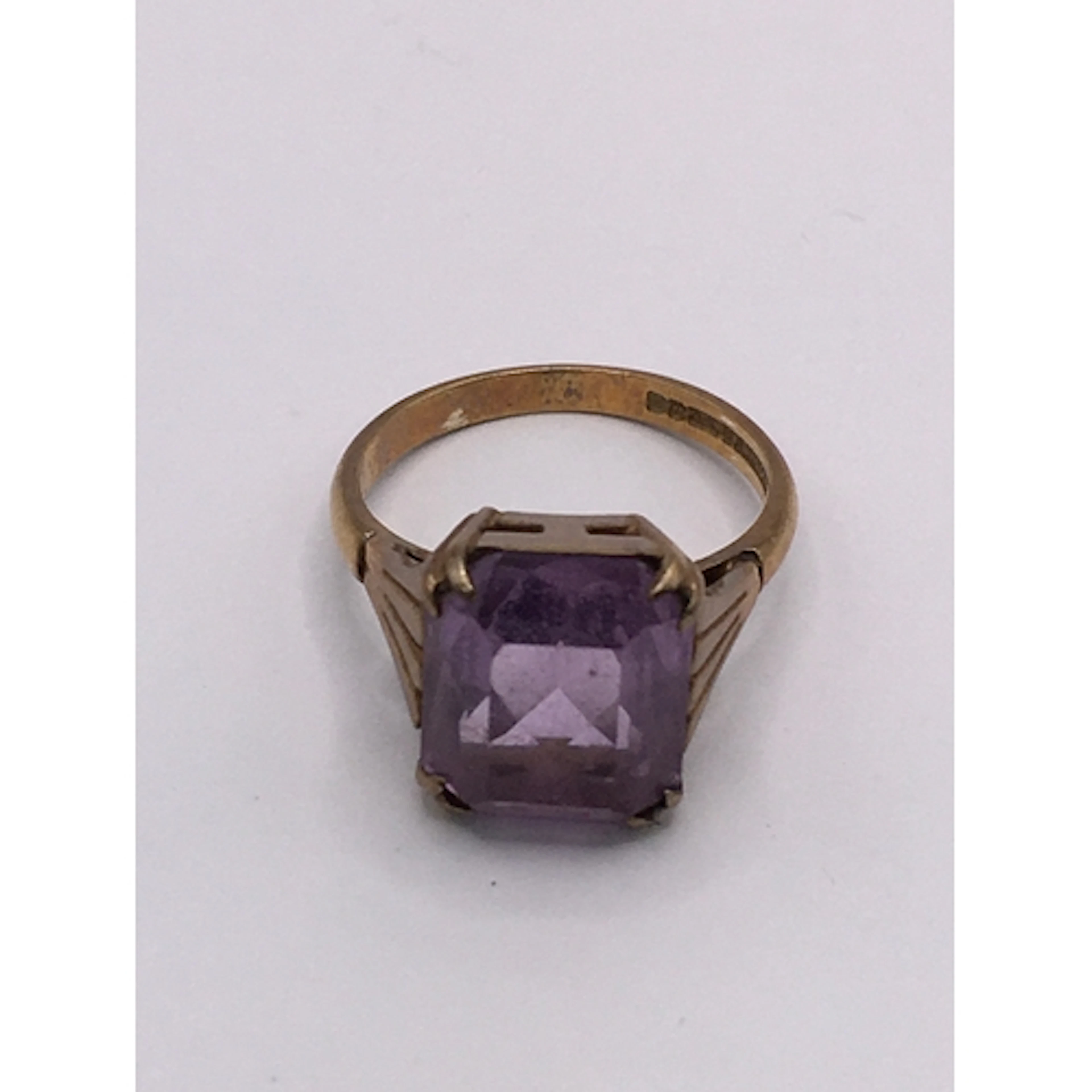 A 9ct gold ring set with an amethyst coloured square stone. ...