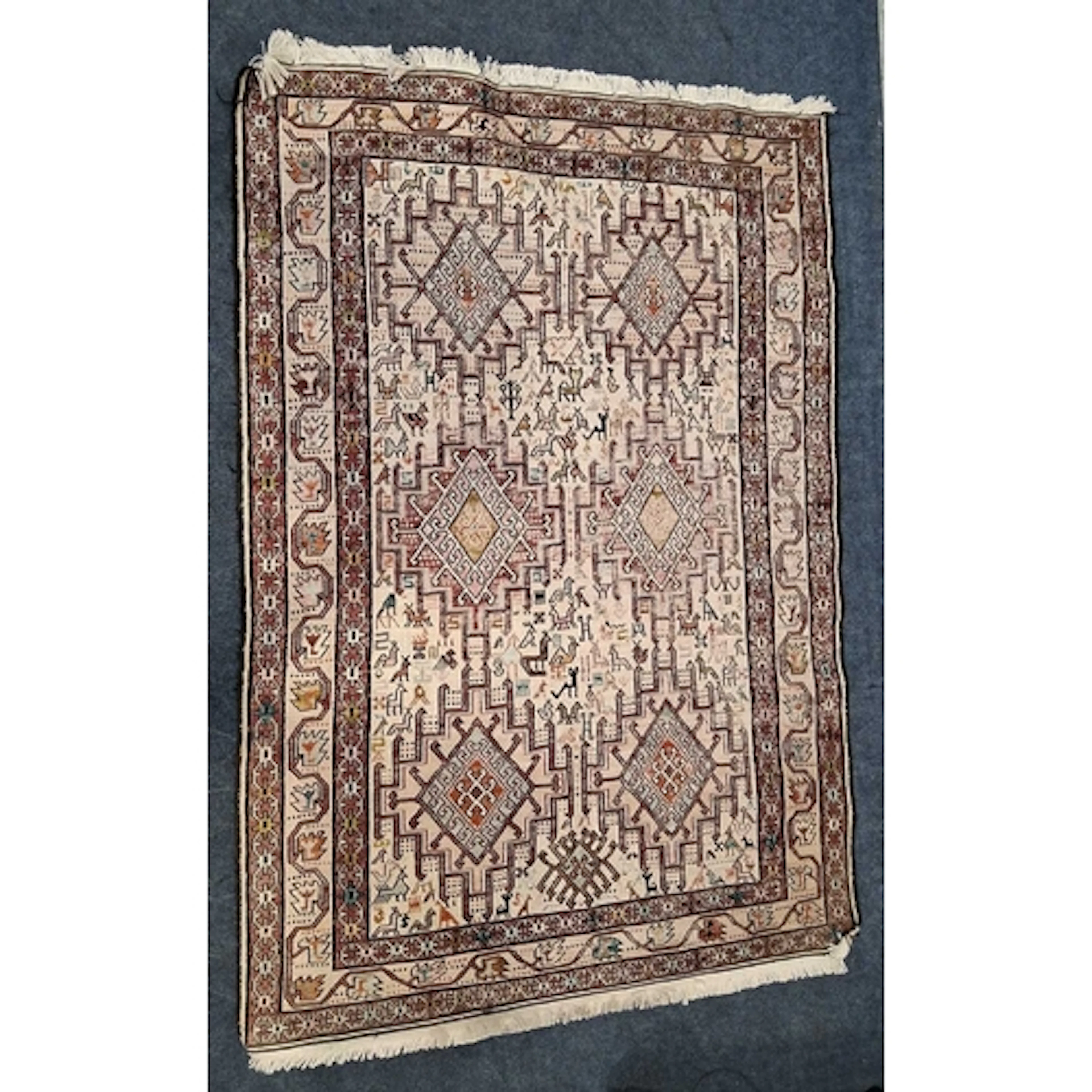 A SMALL CREAM GROUND RECTANGULAR WOOLLEN RUG, depicting vari...