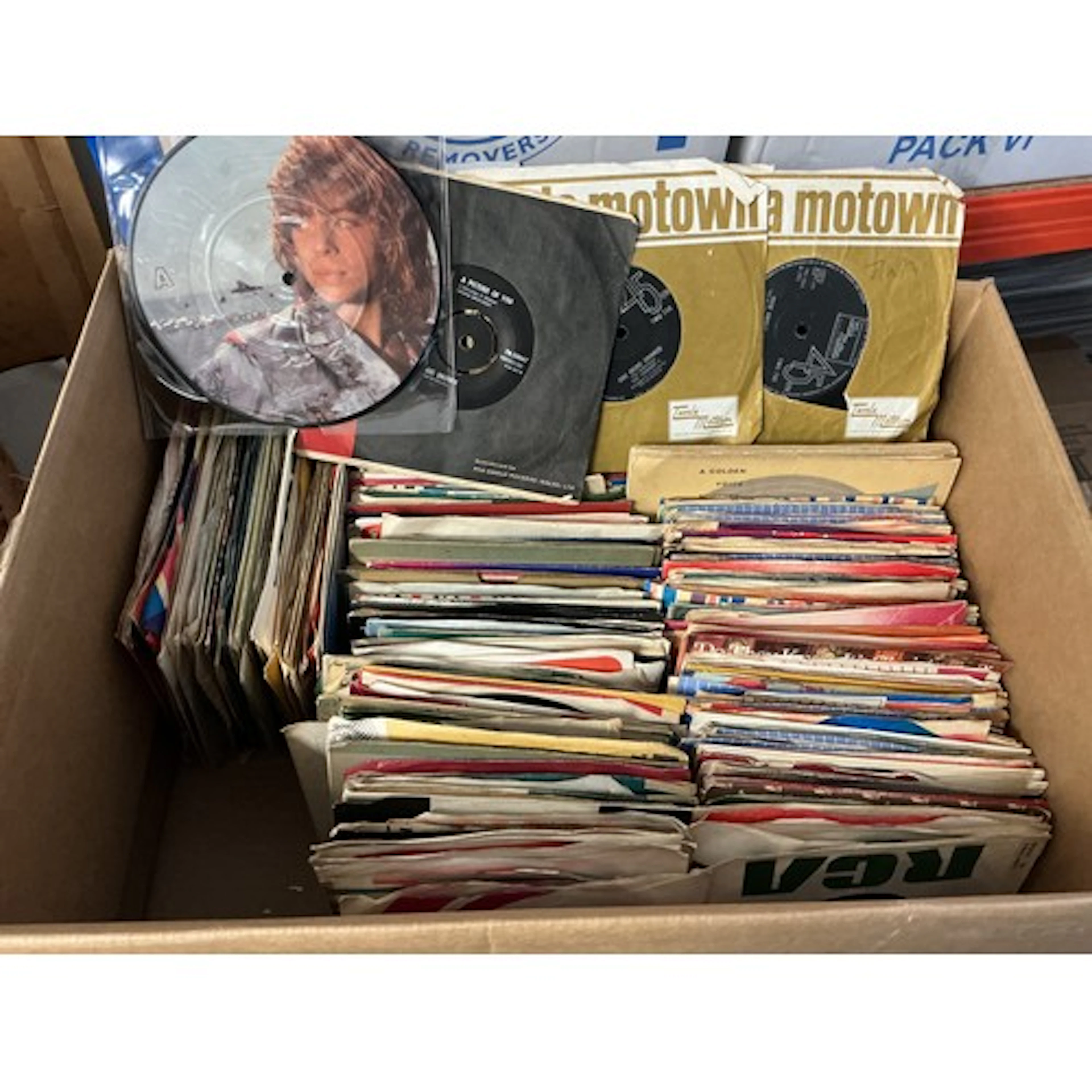 A record case and a box of 7” singles by various artists fro...
