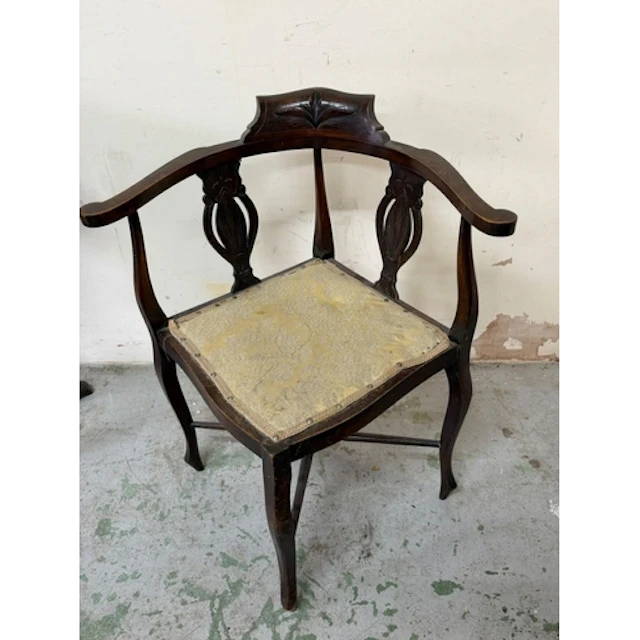 An Edwardian mahogany corner chair with a carved top crest a...
