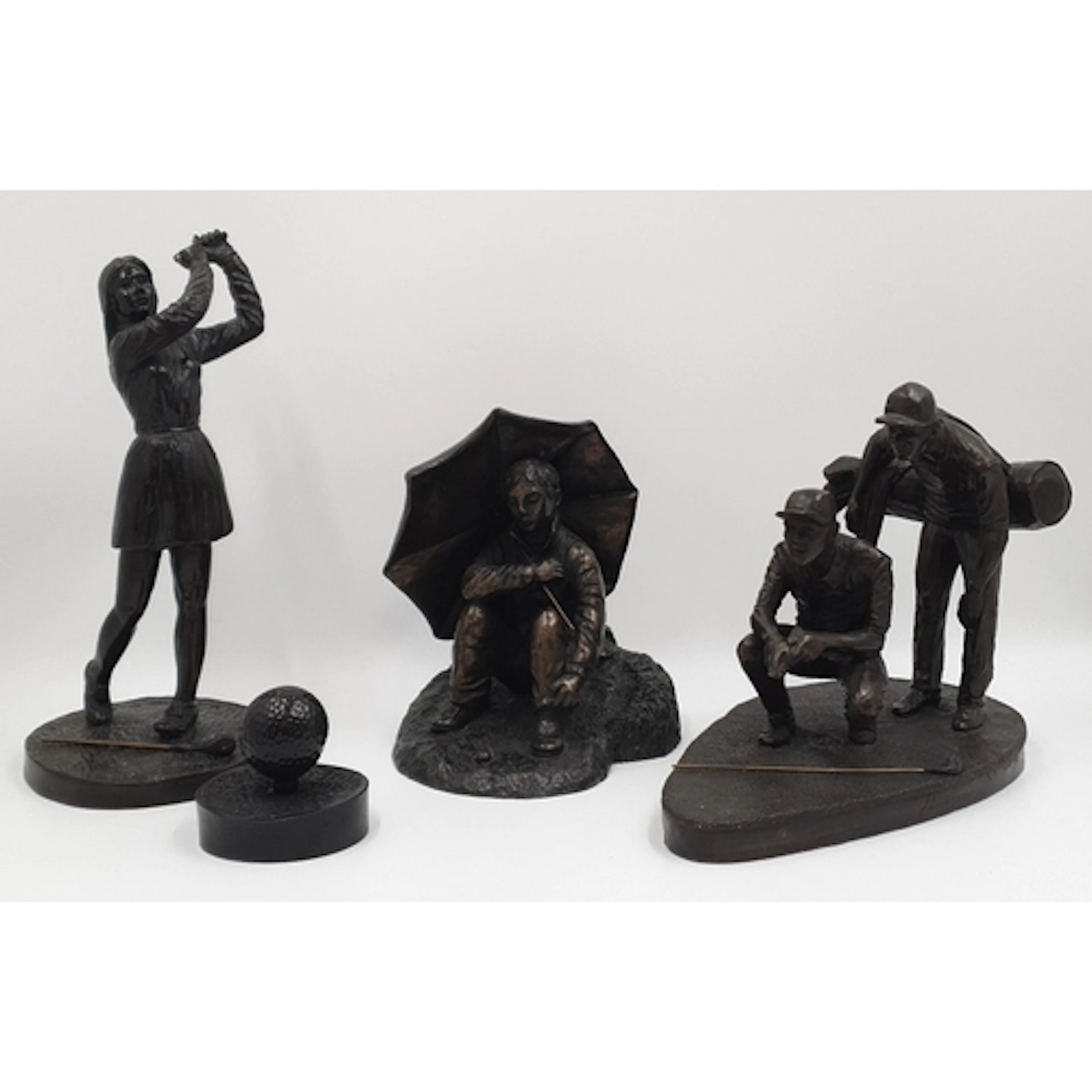 Four golf-themed ornaments comprising golfer, seated spectat...