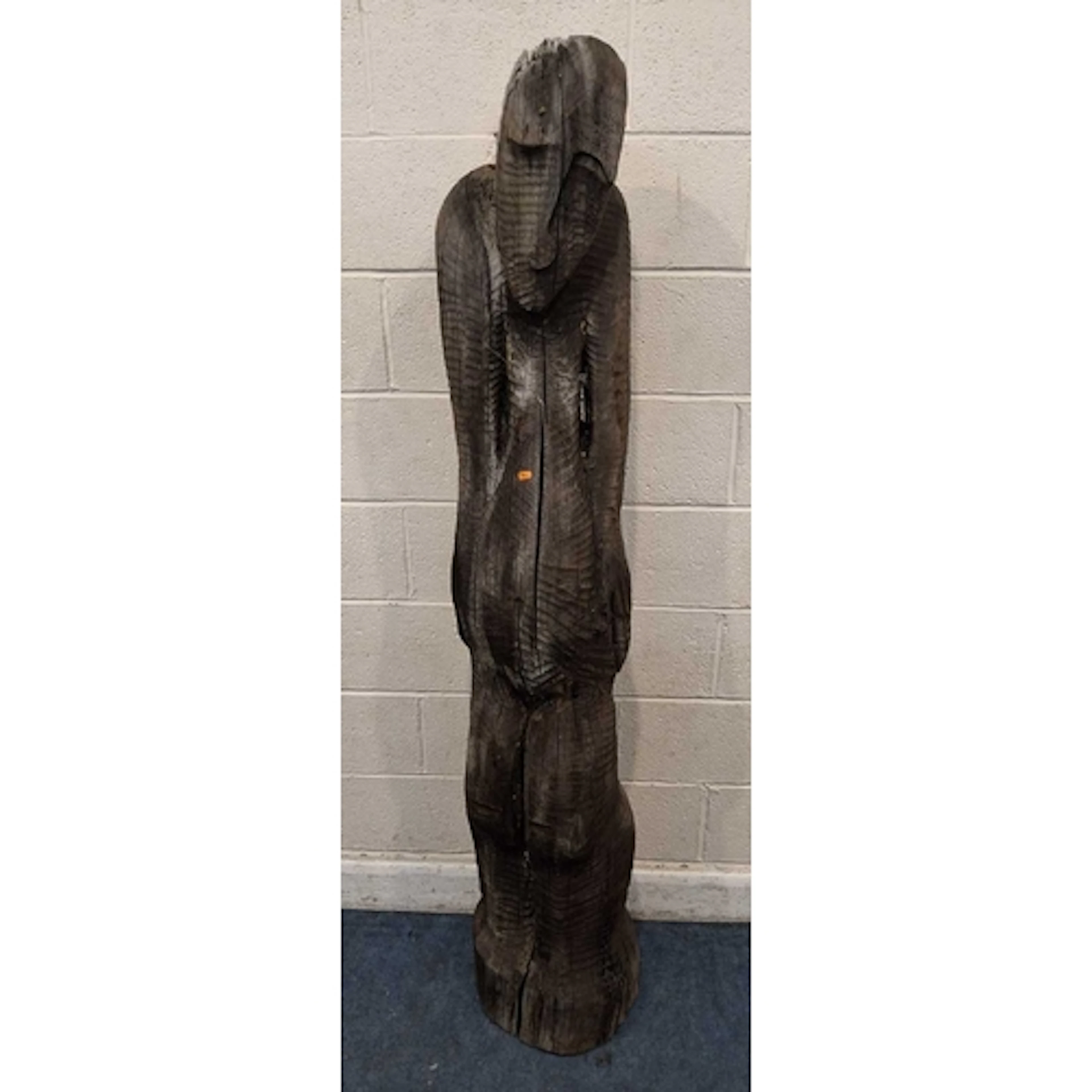A LARGE CARVED TIMBER HUMANOID FIGURE, with a long face, arm...