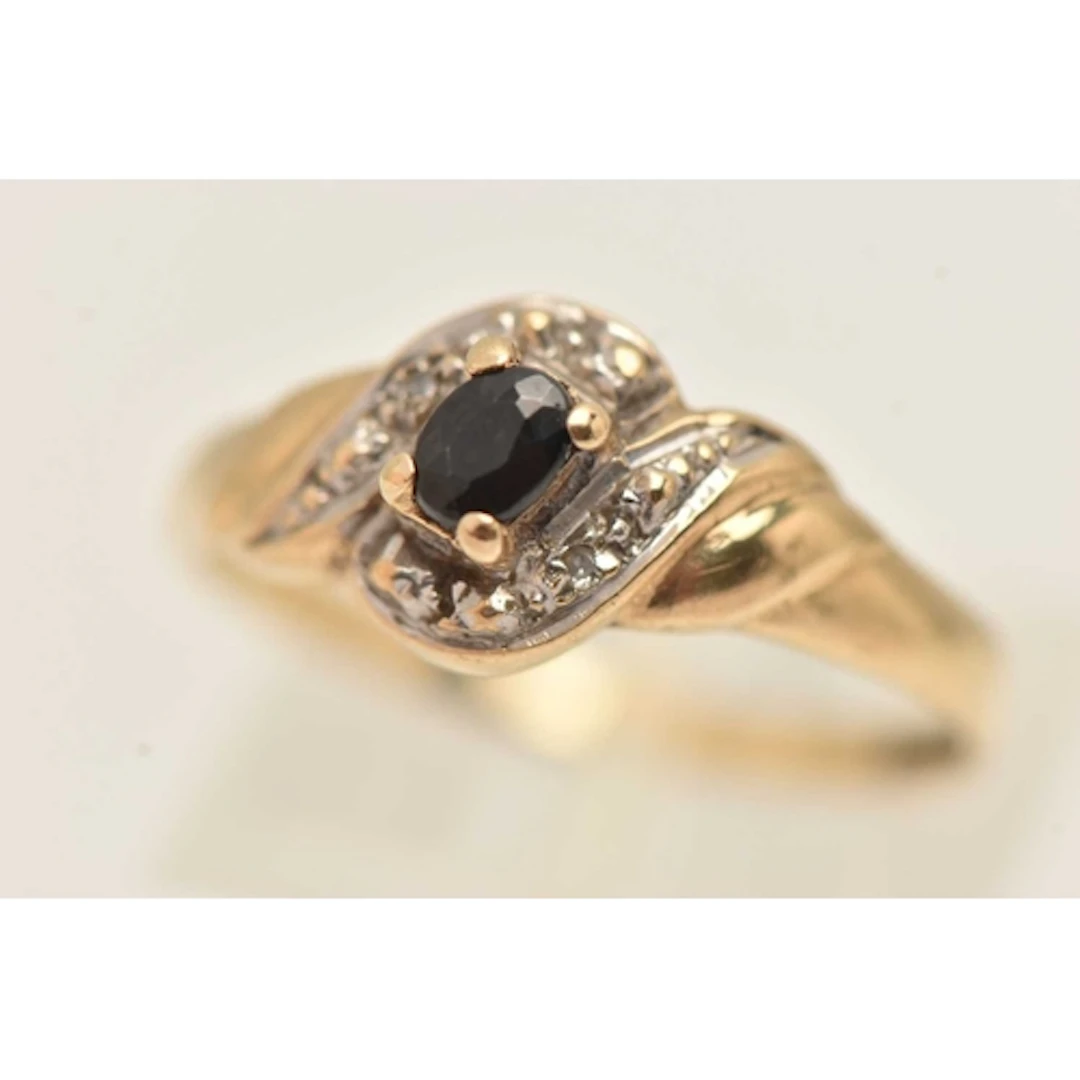 A 9CT YELLOW GOLD GEM SET RING, an oval cut sapphire, flanke...