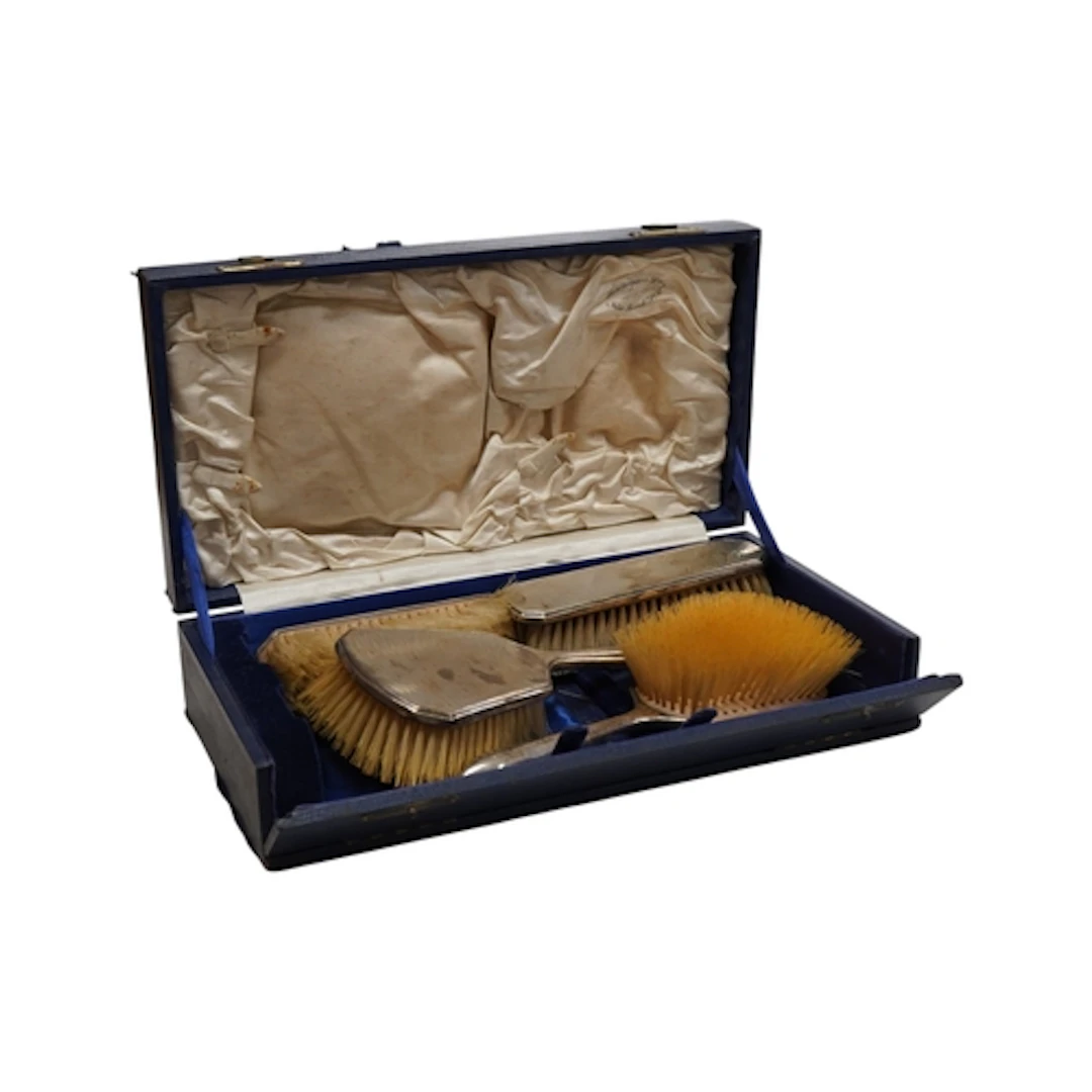 A cased George V silver mounted four piece brush set by Hort...