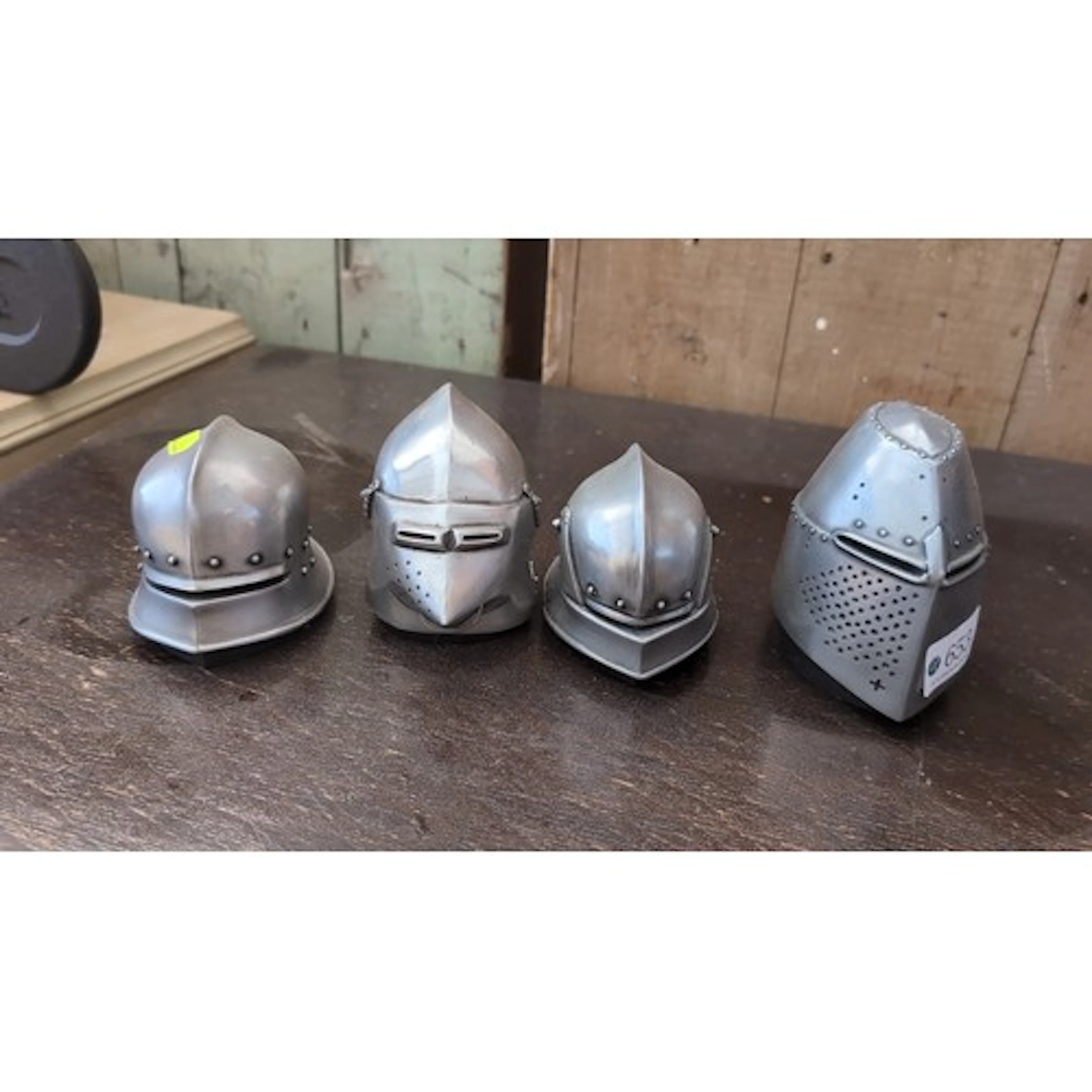 A group of miniature medieval-style knight’s helmets, as pap...