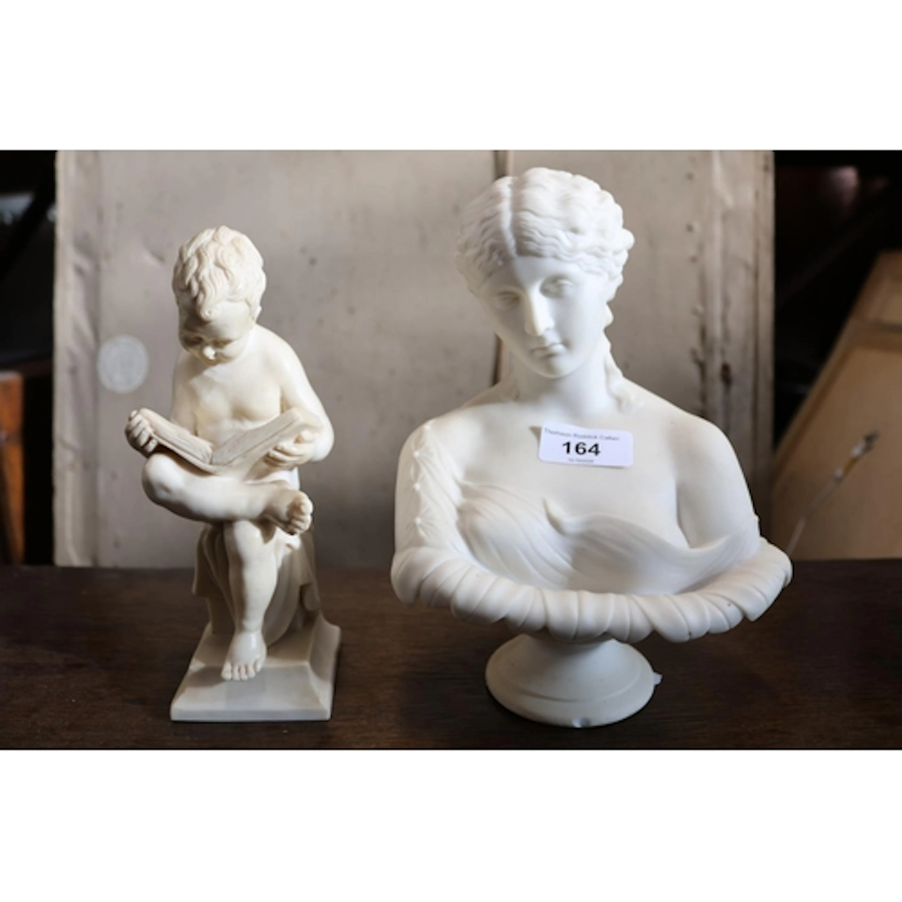 Bust figure of a maiden and a figure of a boy reading.