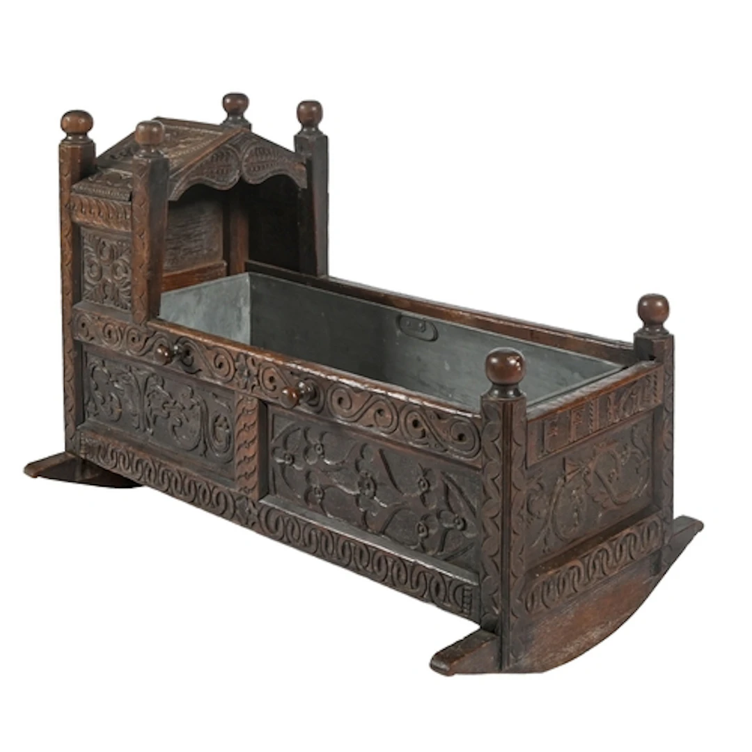 A James I oak cradle, dated 1615, the panels and frame carve...