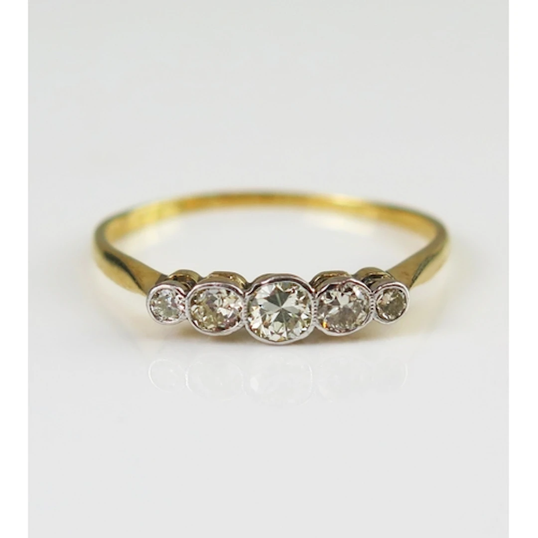 A diamond five stone ring in a precious yellow metal setting...