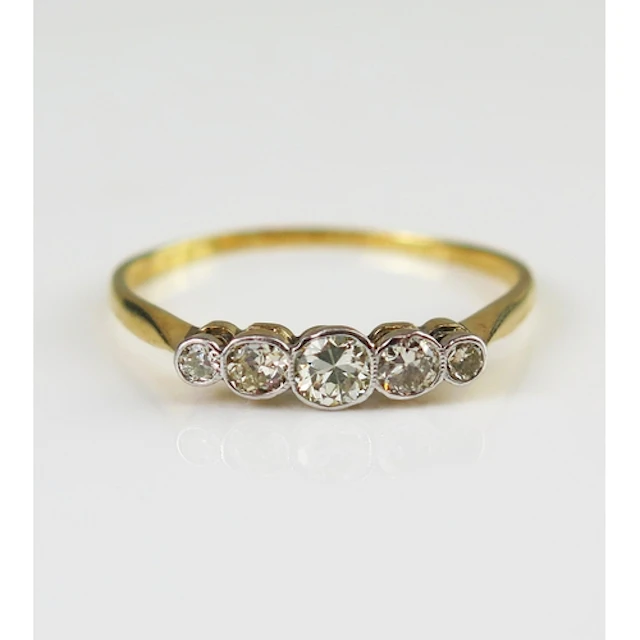 A diamond five stone ring in a precious yellow metal setting...