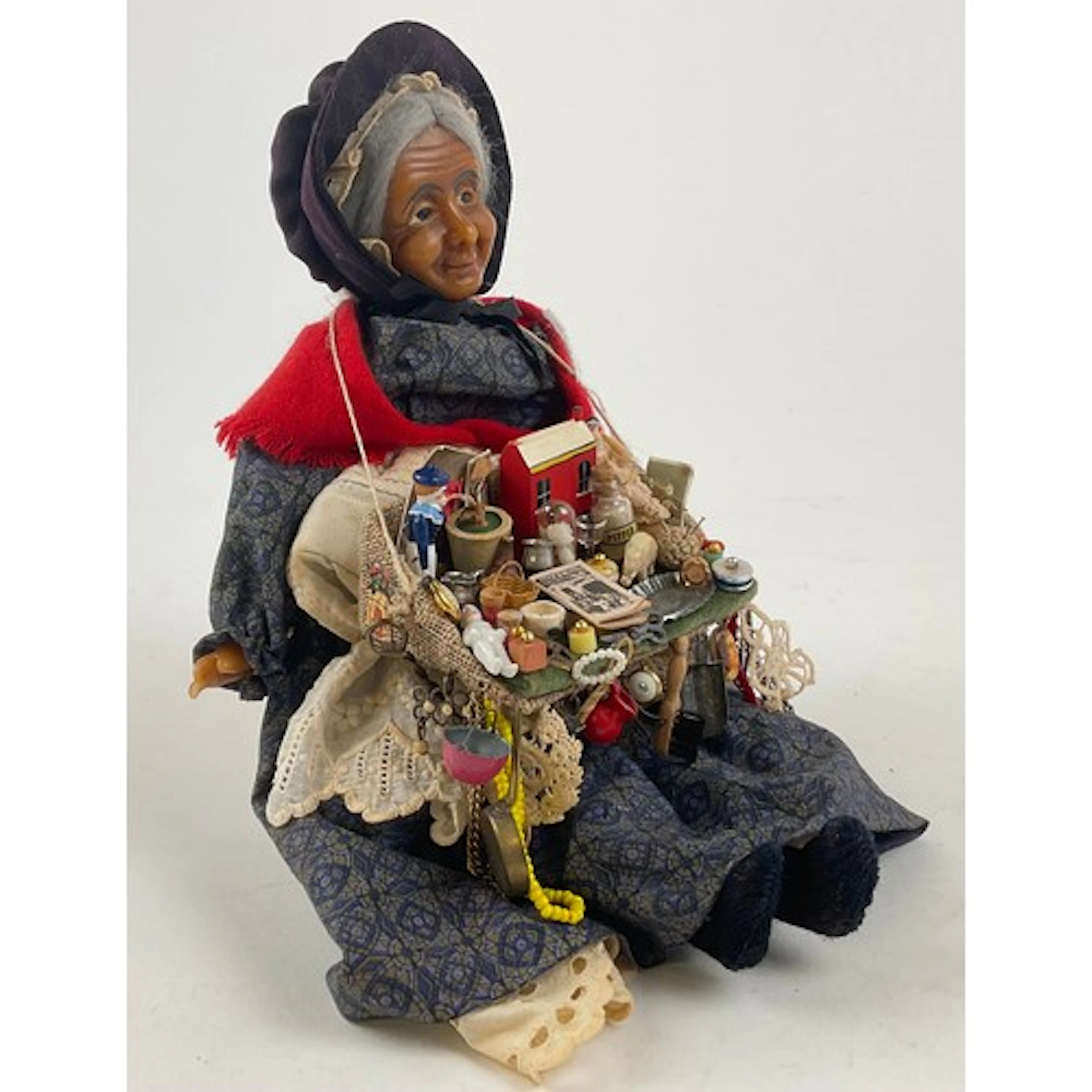 A Victorian style wax street peddler doll, purple/grey hair,...