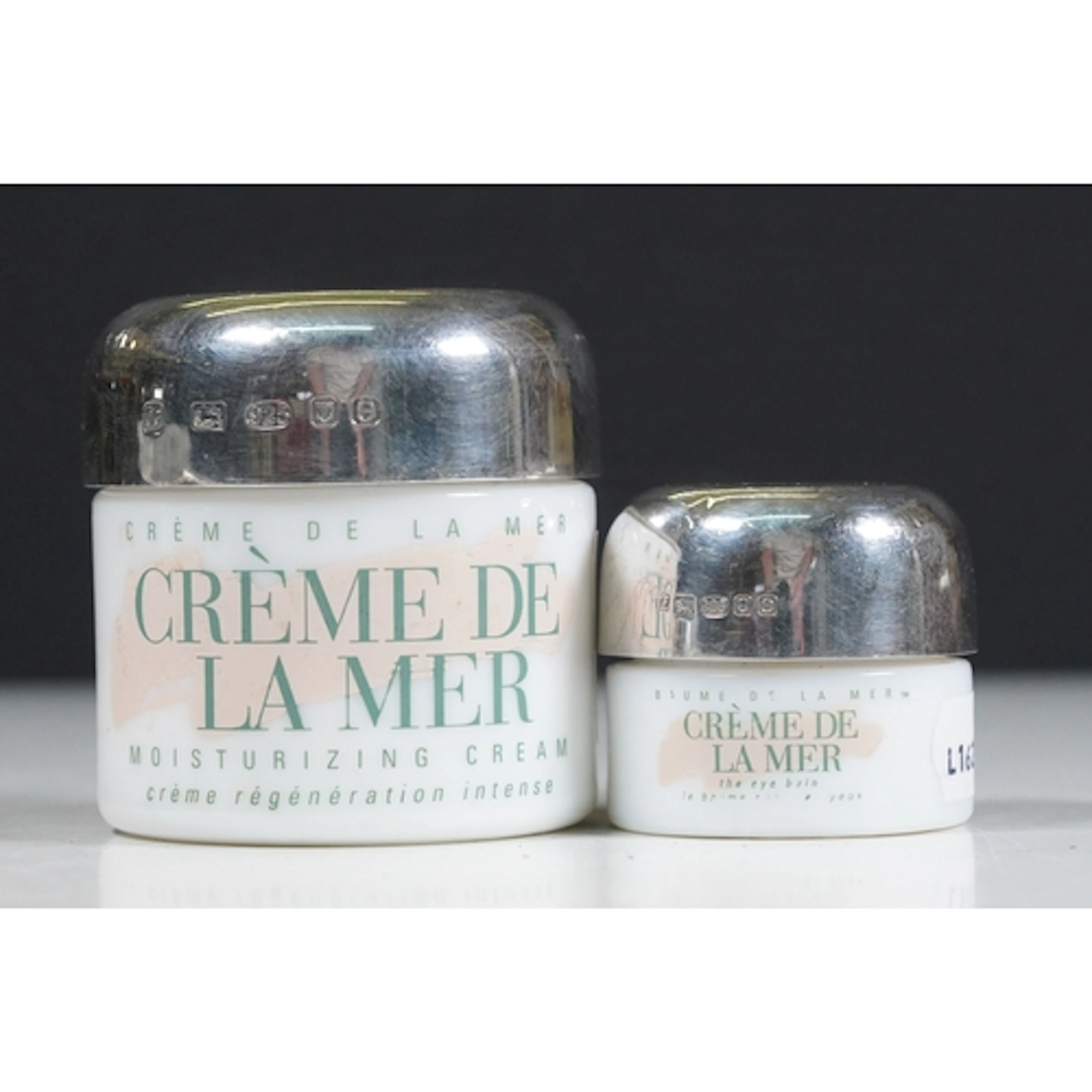 Two Creme De La Mer ceramic cream pots, with hallmarked silv...