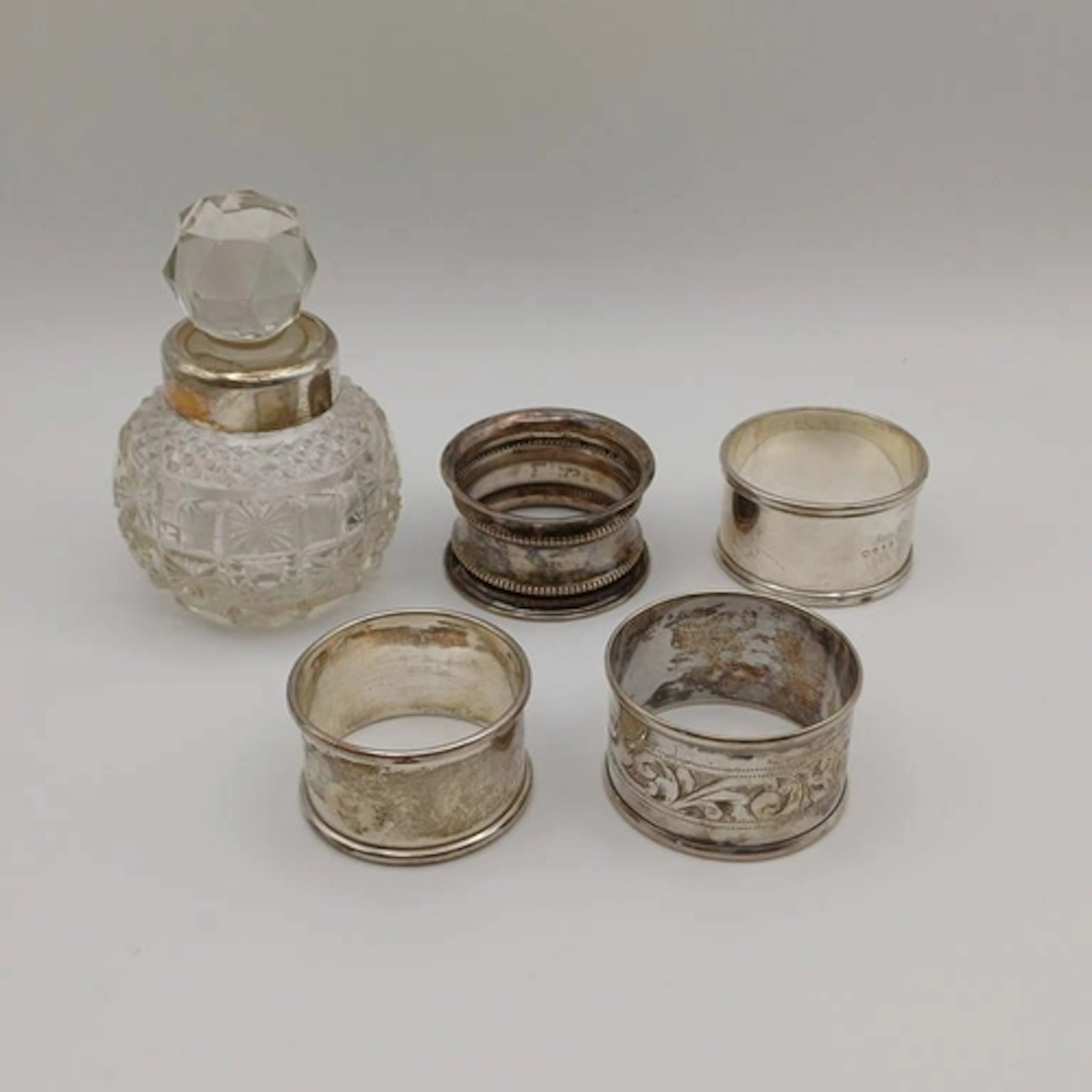 4 SILVER NAPKIN RINGS & A SILVER MOUNTED CUT GLASS SCENT BOT...