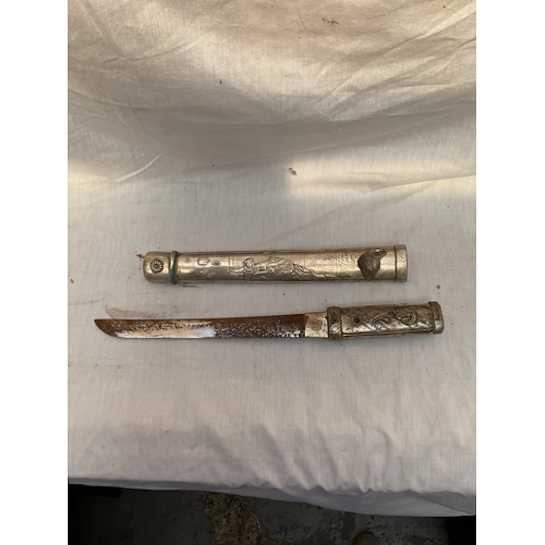 Ornate metal Tanto dagger with erotic scenes.