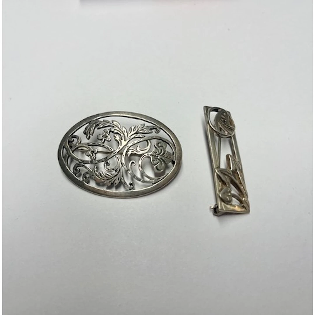 Silver Mackintosh style brooch with another. (2)