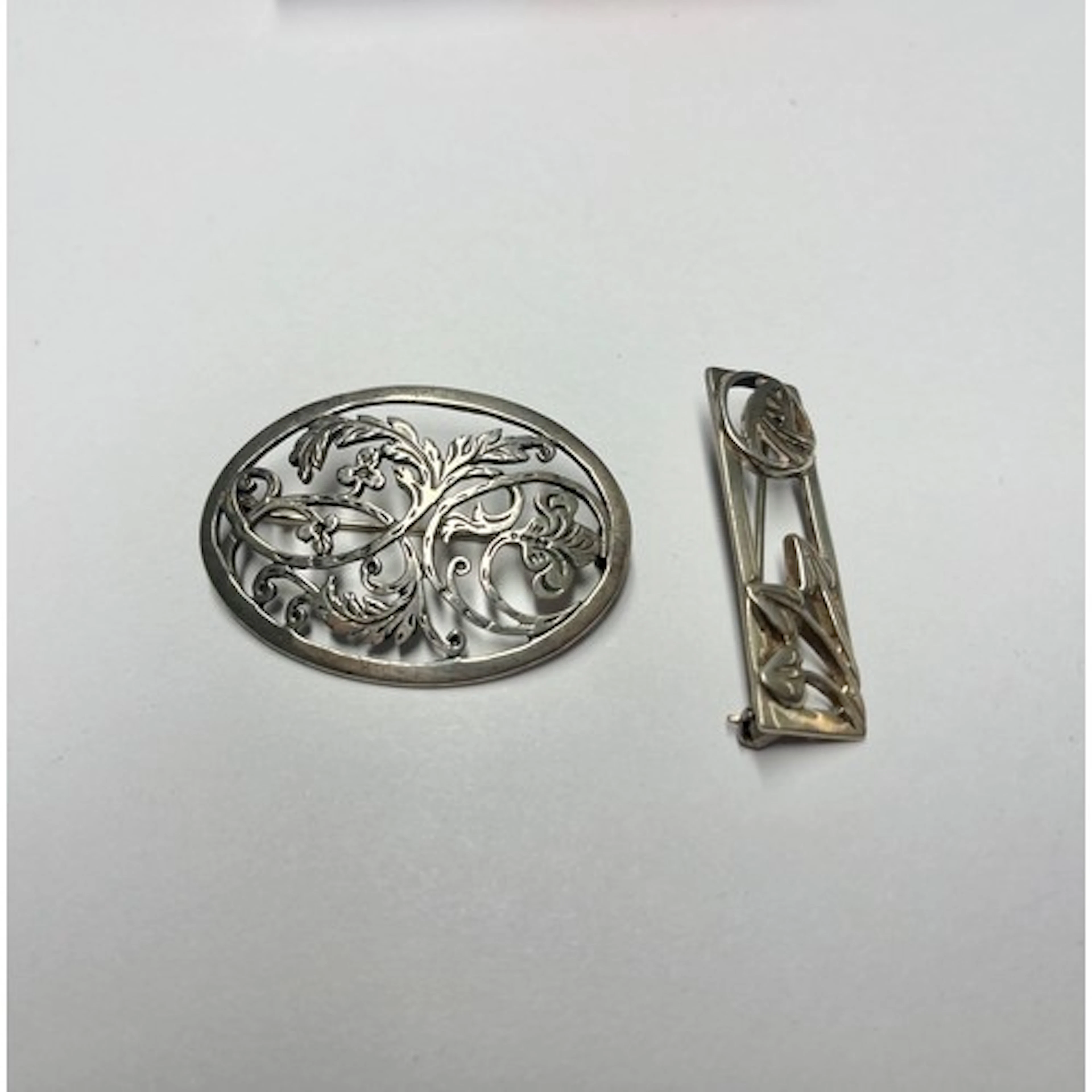 Silver Mackintosh style brooch with another. (2)