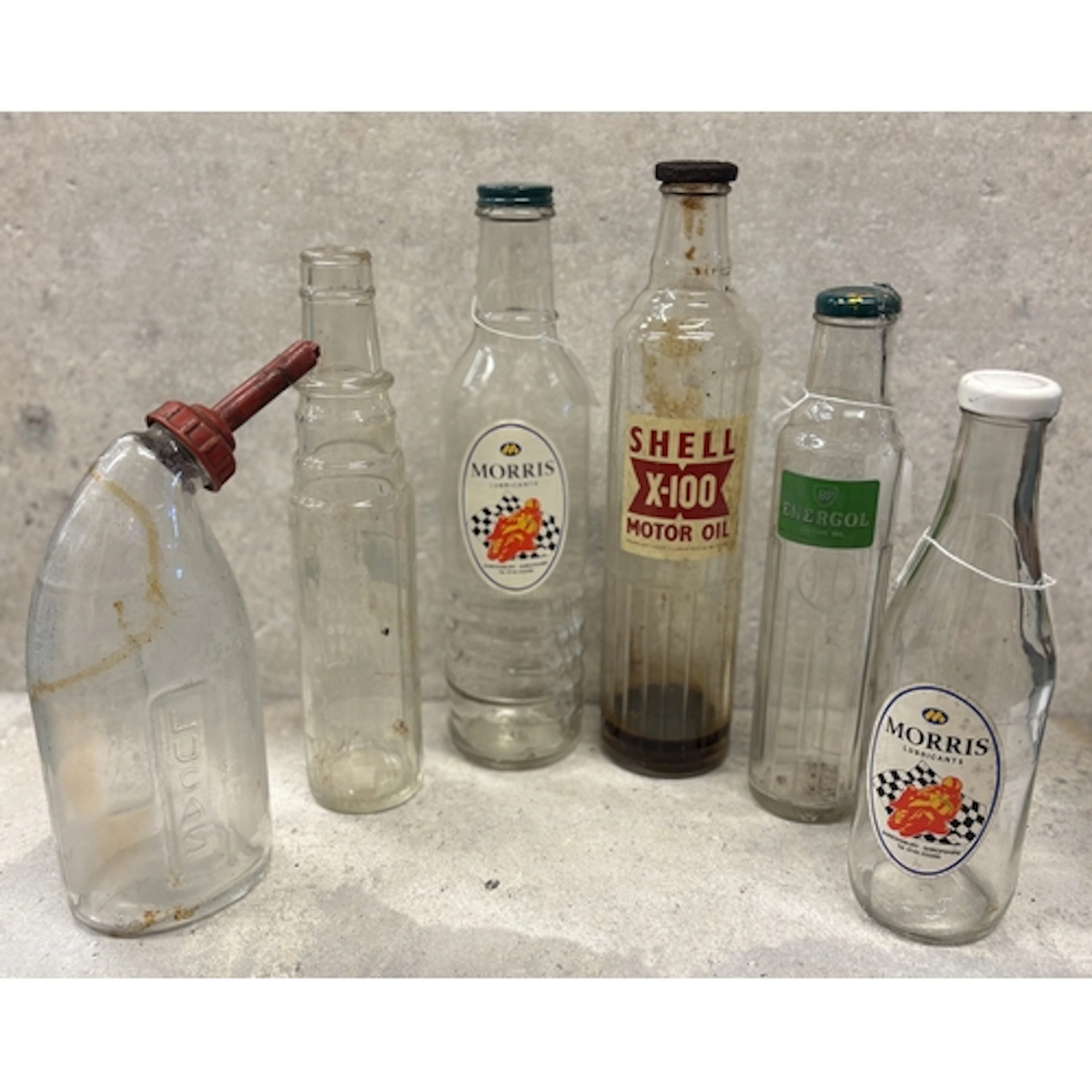 A collection of various vintage motor oil glass bottles to i...