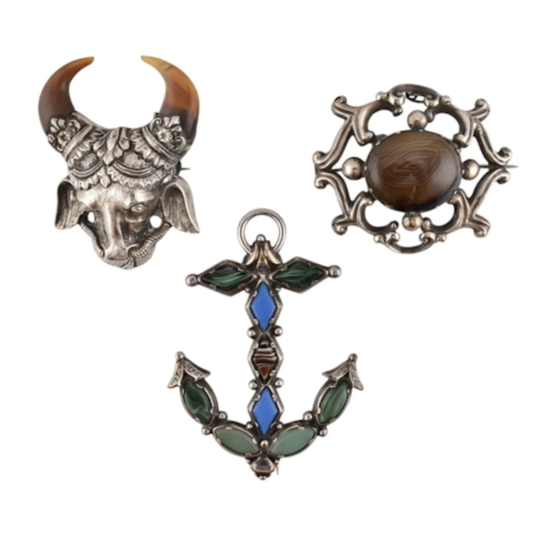 Three white metal statement brooch pins. To include: a white...