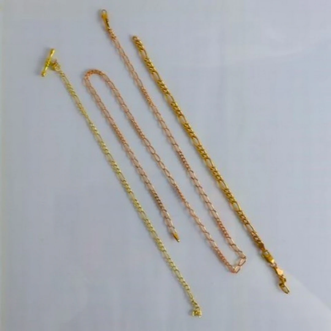 A selection of three yellow metal chains, including a figaro...