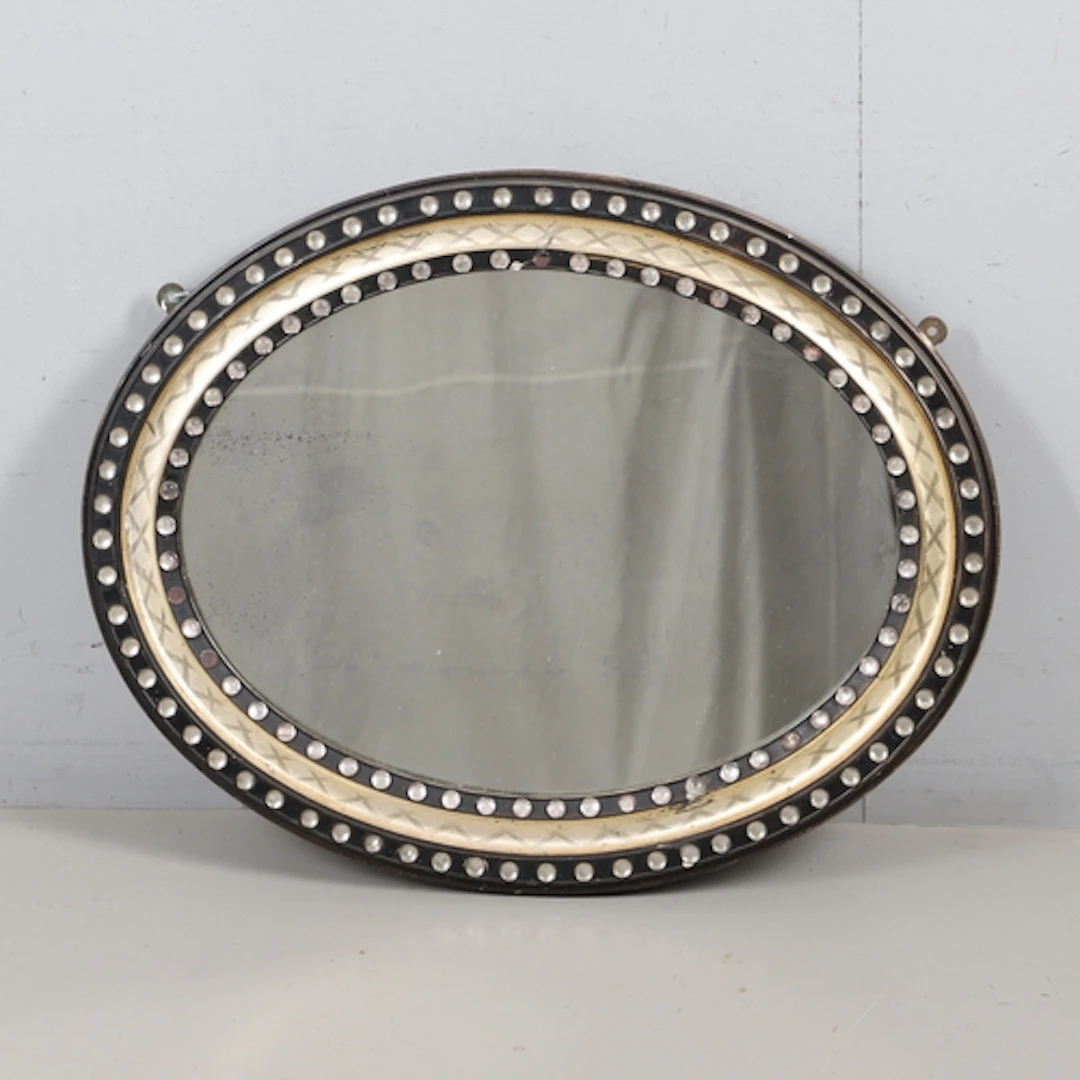A 19TH CENTURY IRISH OVAL WALL MIRROR. the ebonised and parc...
