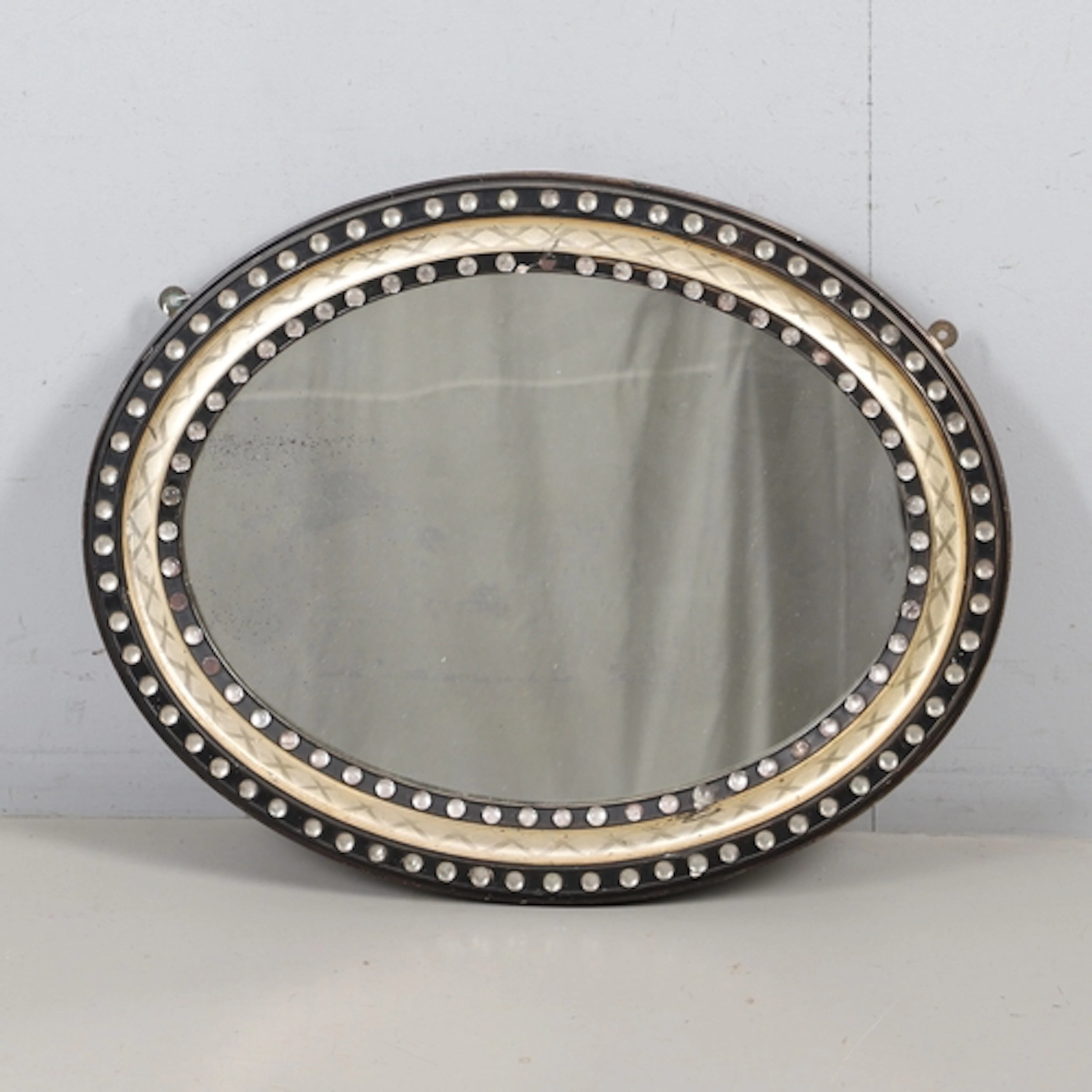 A 19TH CENTURY IRISH OVAL WALL MIRROR. the ebonised and parc...
