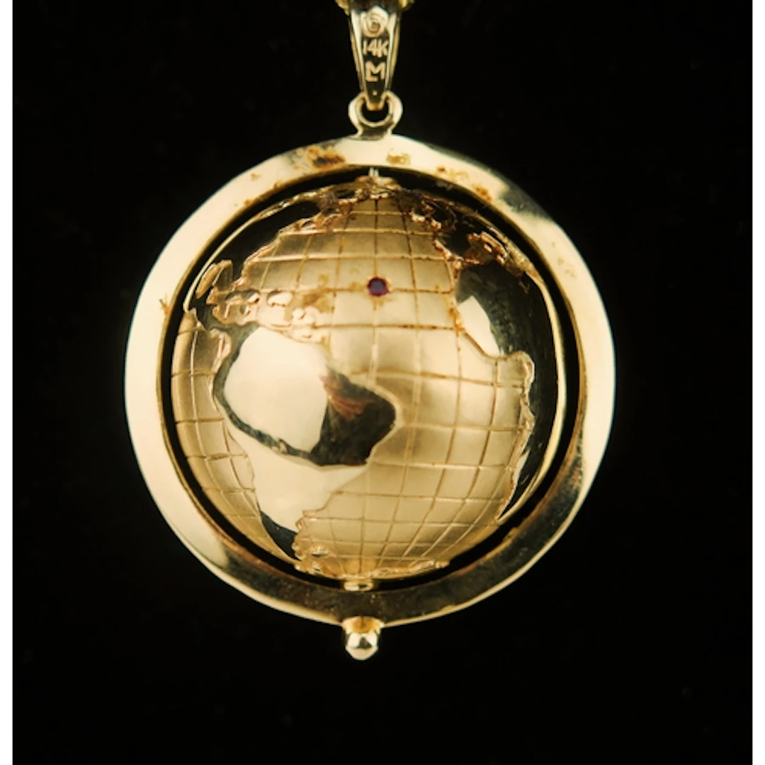 A ruby and sapphire mounted 14K yellow gold spinning globe p...