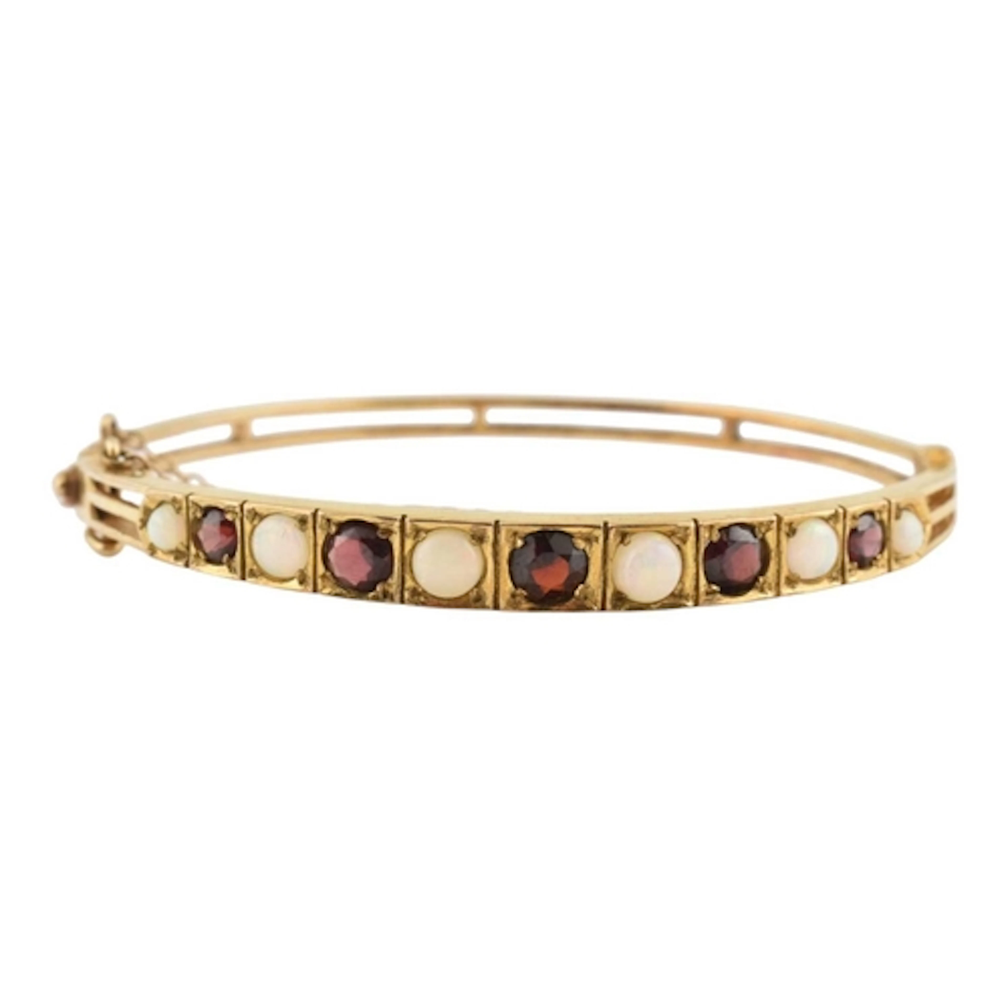 A 1970s hallmarked 9ct gold garnet and opal bangle. The bang...