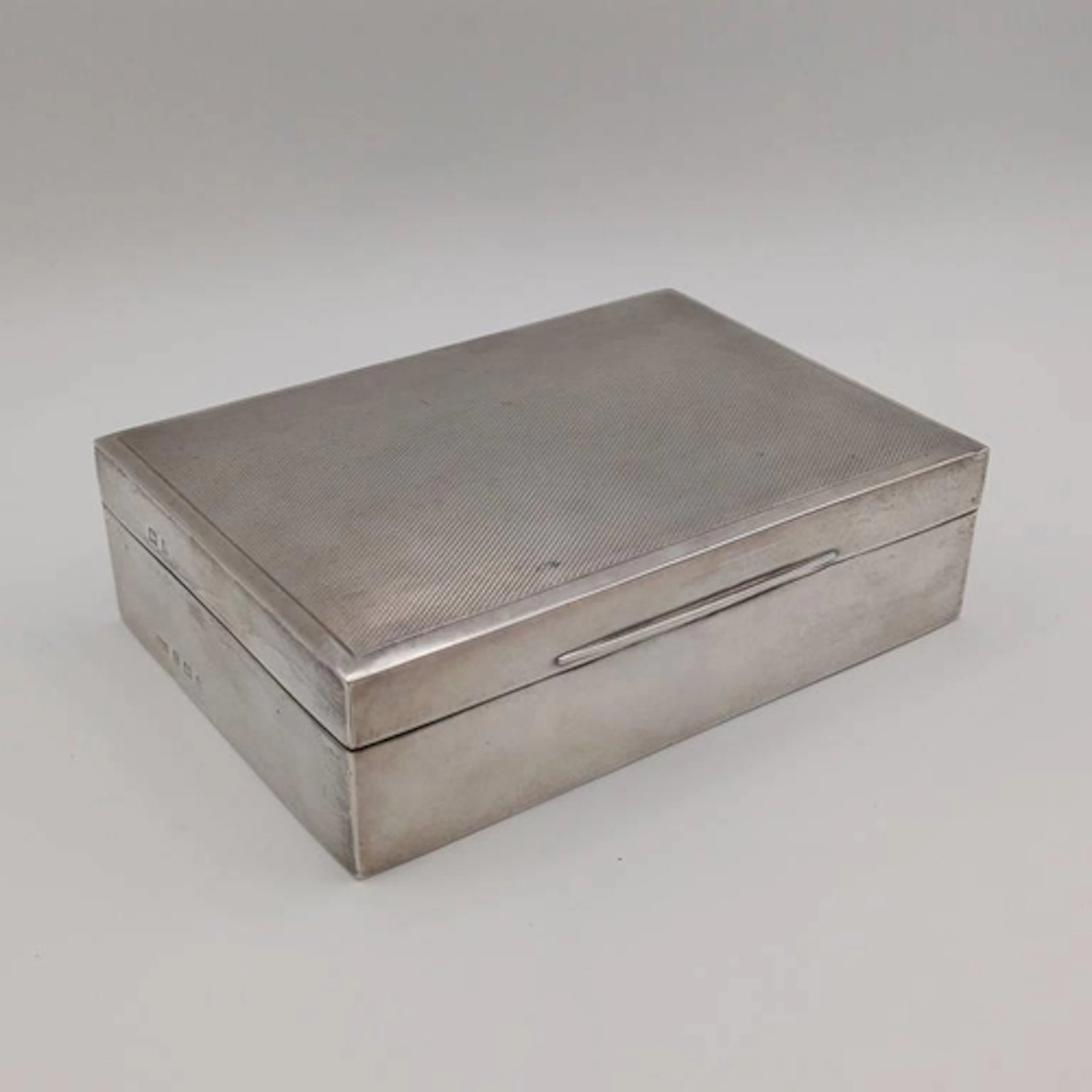 A SILVER CIGARETTE BOX WITH ENGINE TURNED LID BY JAMES DIXON...