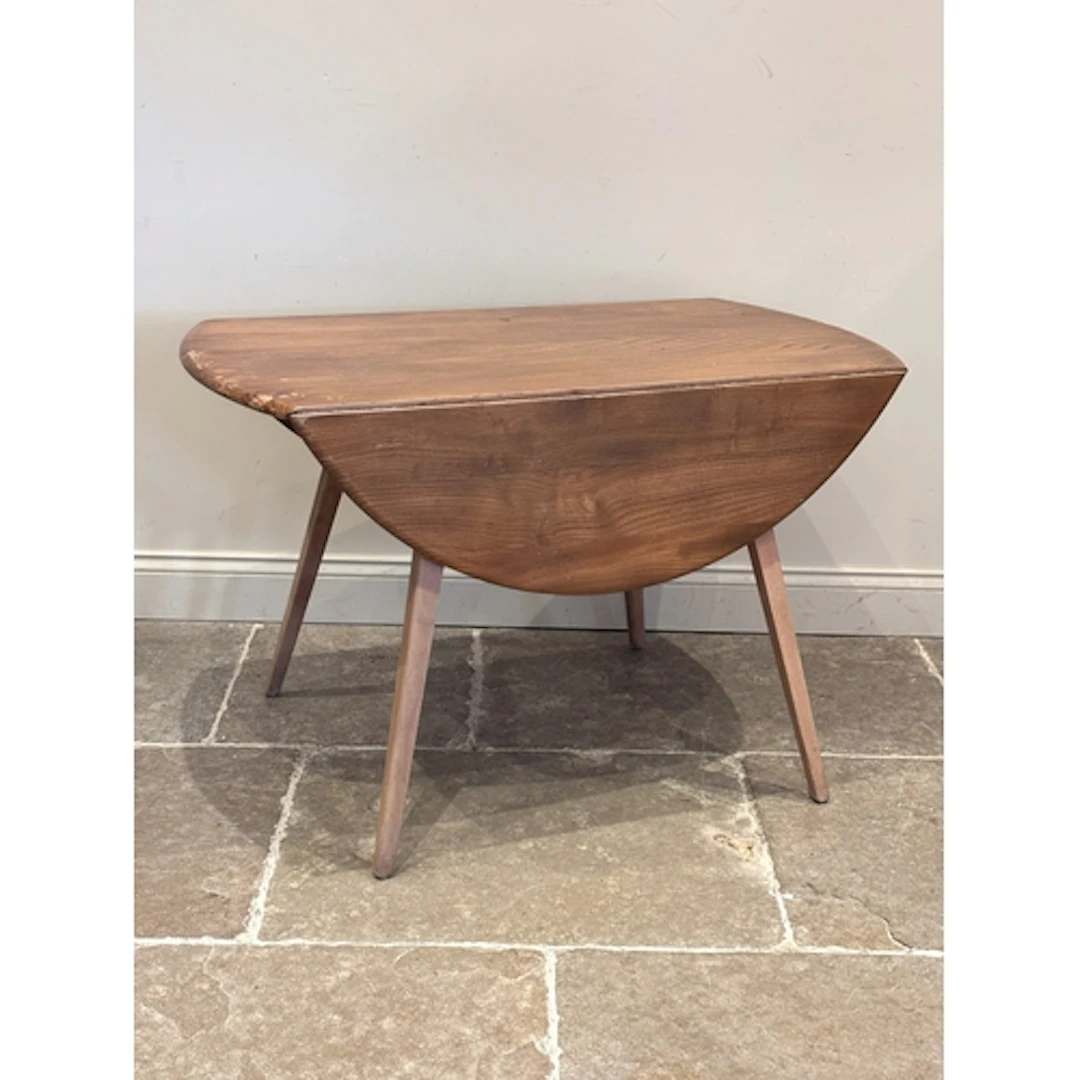 An Ercol Blonde drop leaf table, raised on four outswept leg...