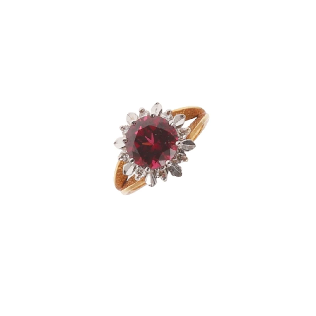 A GARNET AND DIAMOND RING. the circular-cut garnet is set wi...
