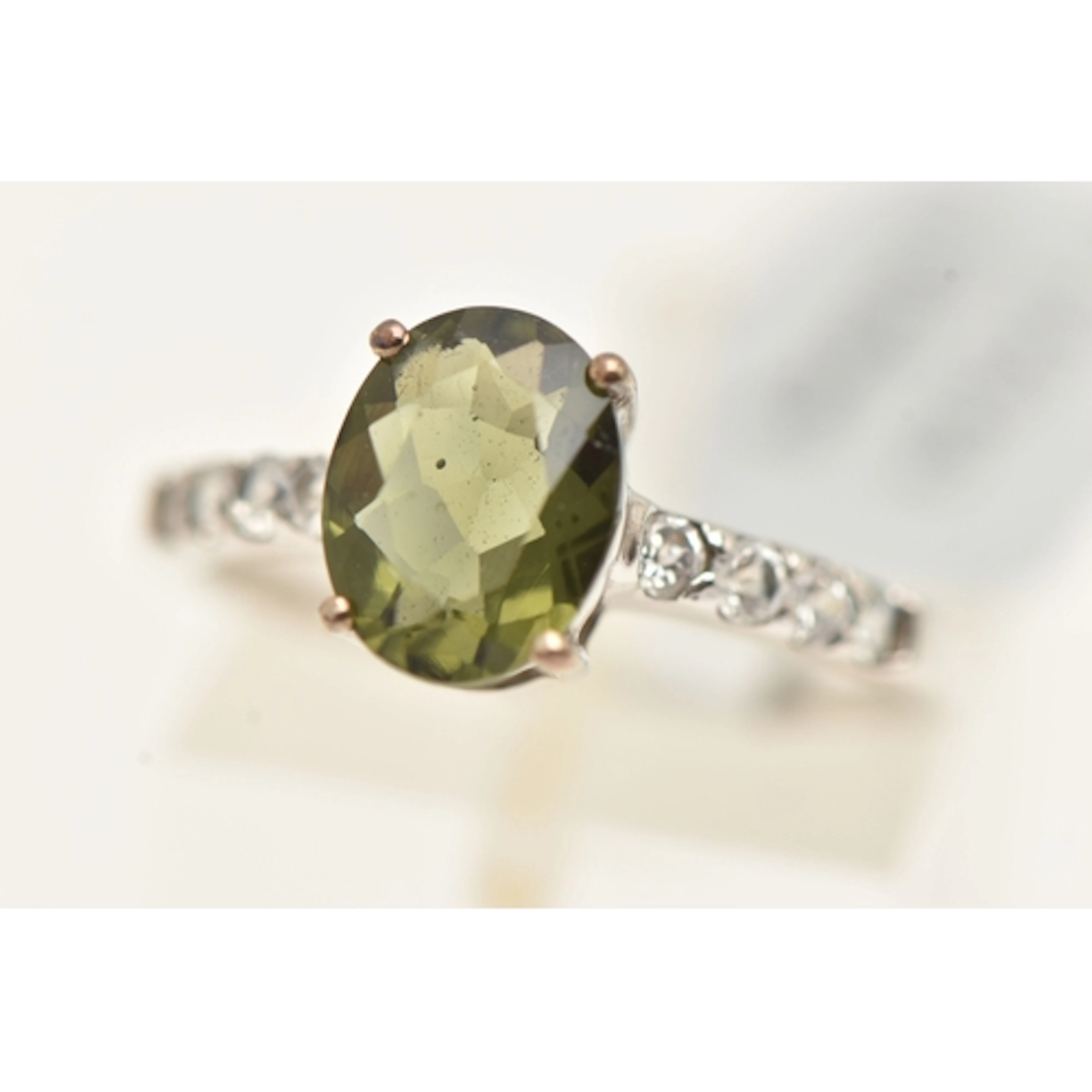 A 9CT WHITE GOLD GEM SET RING, oval cut moldavite, flanked w...
