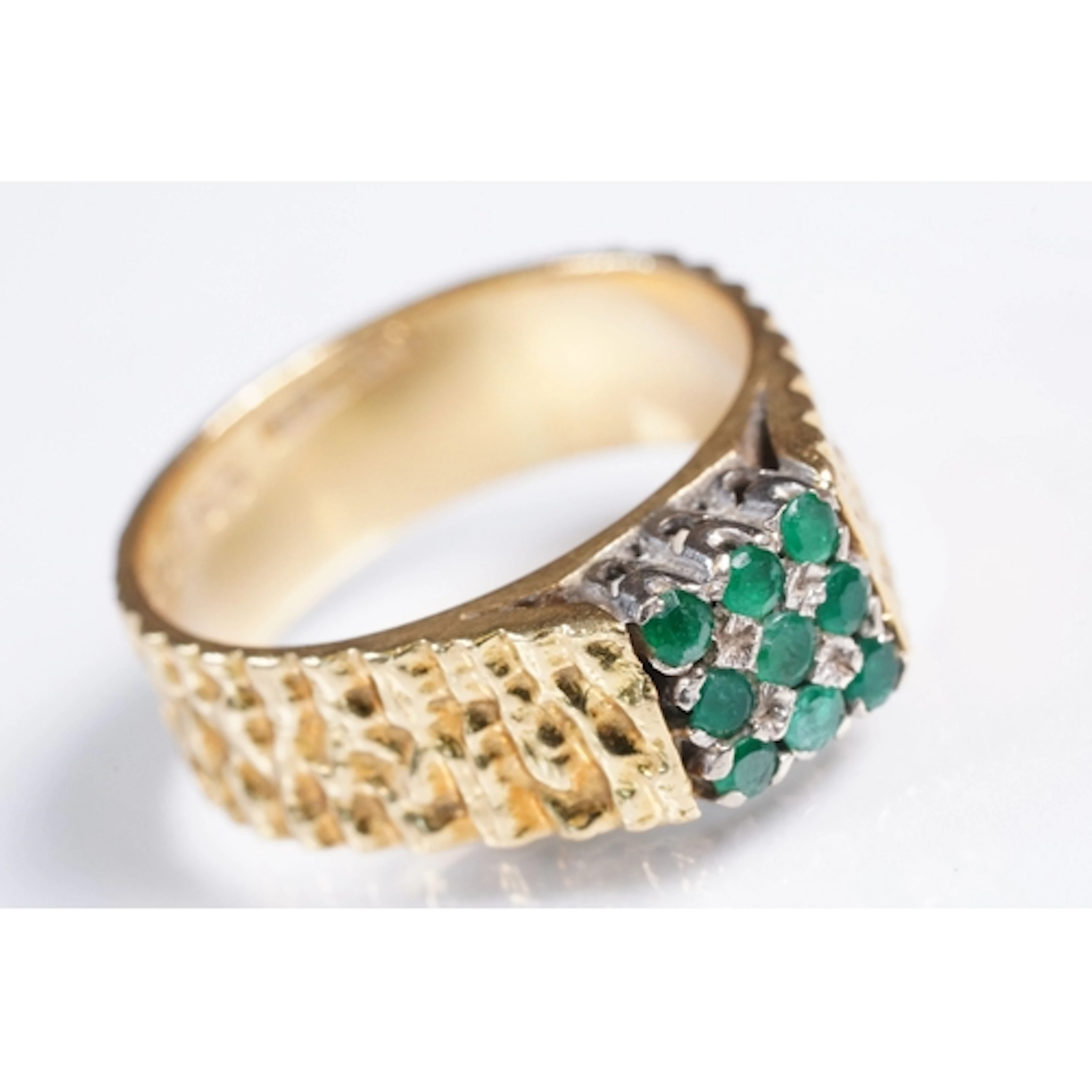18ct gold and emerald ring. The ring being set with nine rou...