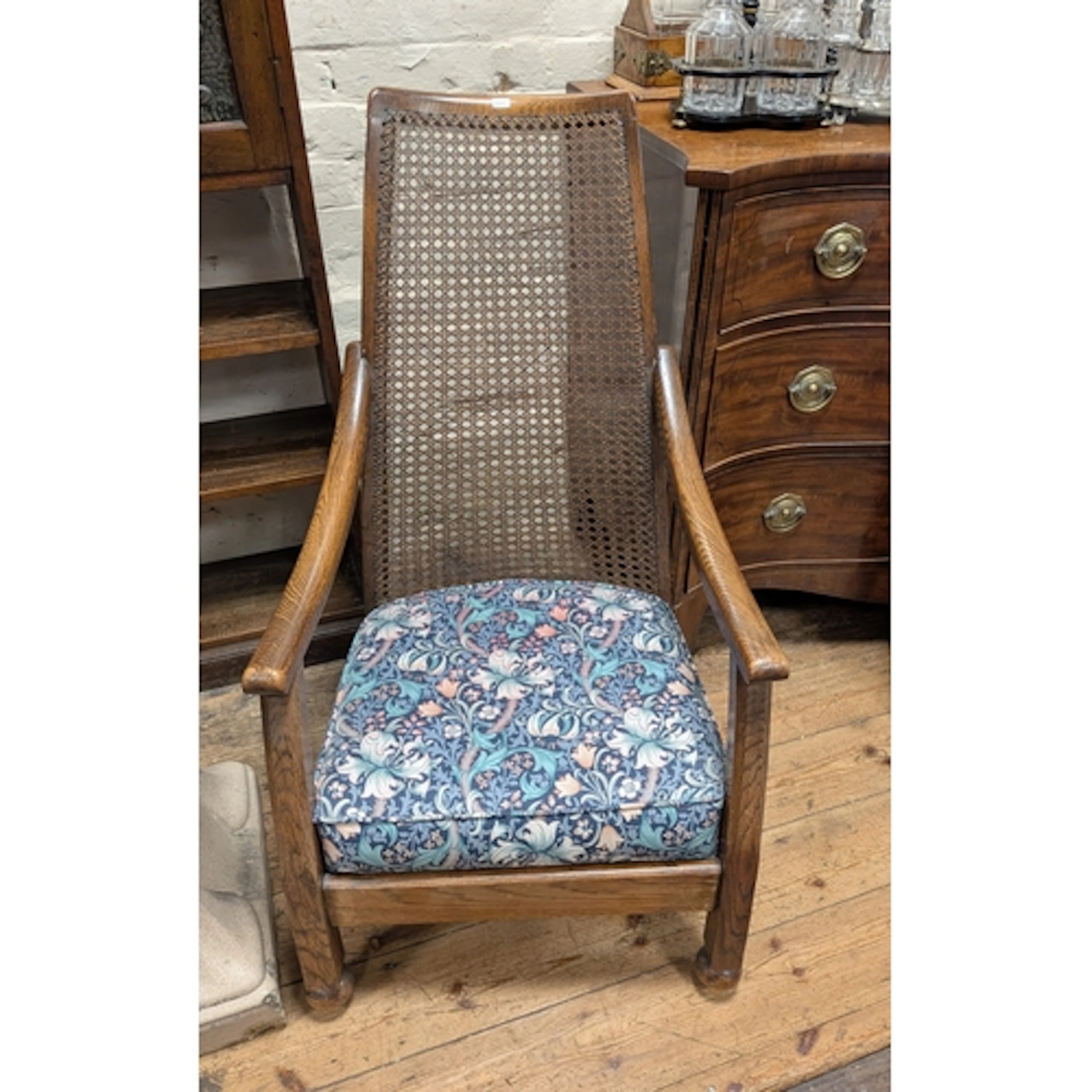 A 1920's open arm chair with cane seat and William Morris fa...
