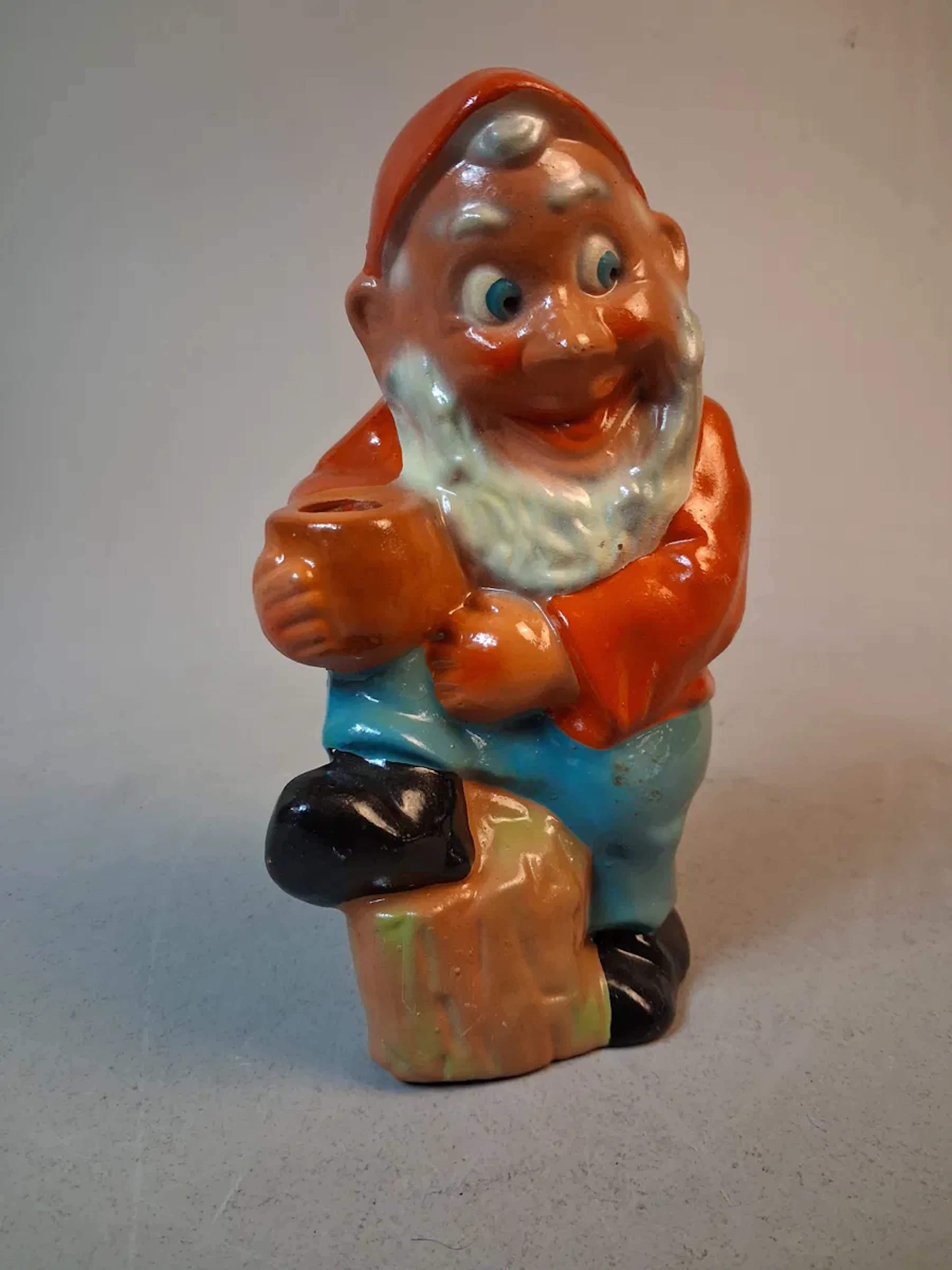 Tomte, figurin, terrakotta. "Tomte som luta sig mot stubben & håller