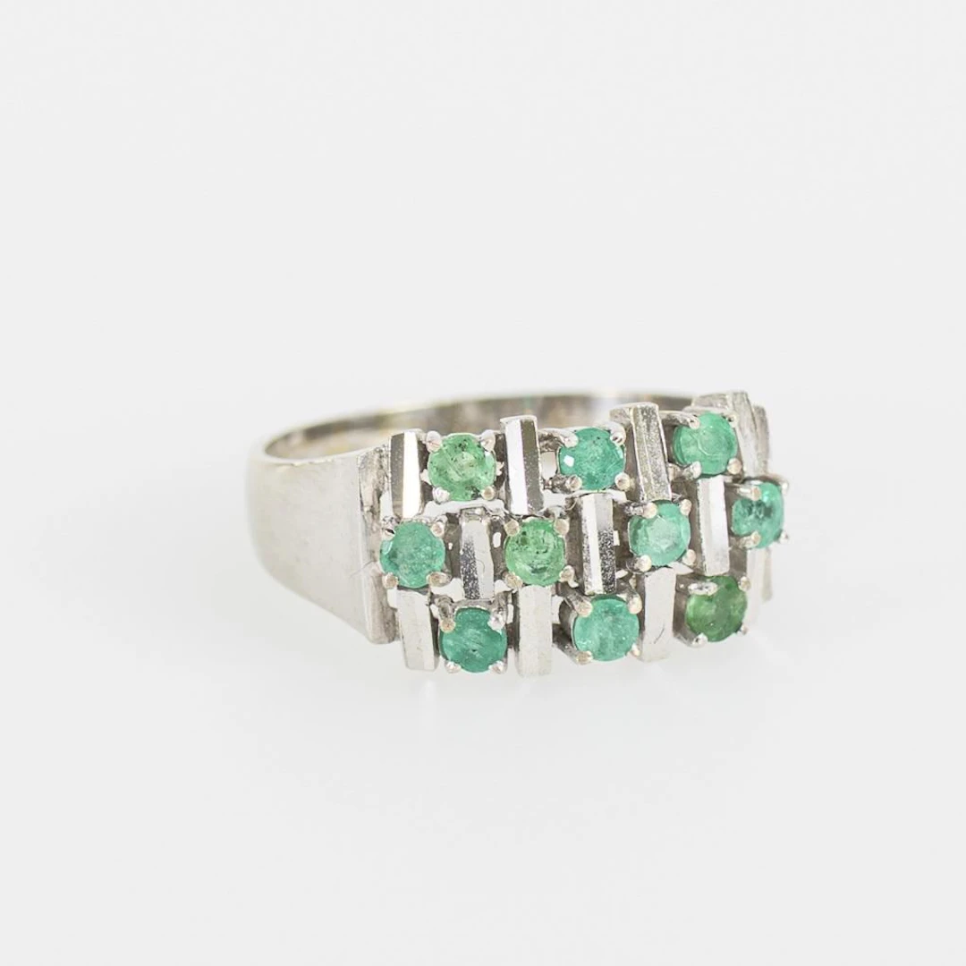 Vintage ring with green gemstones, likely emeralds.
