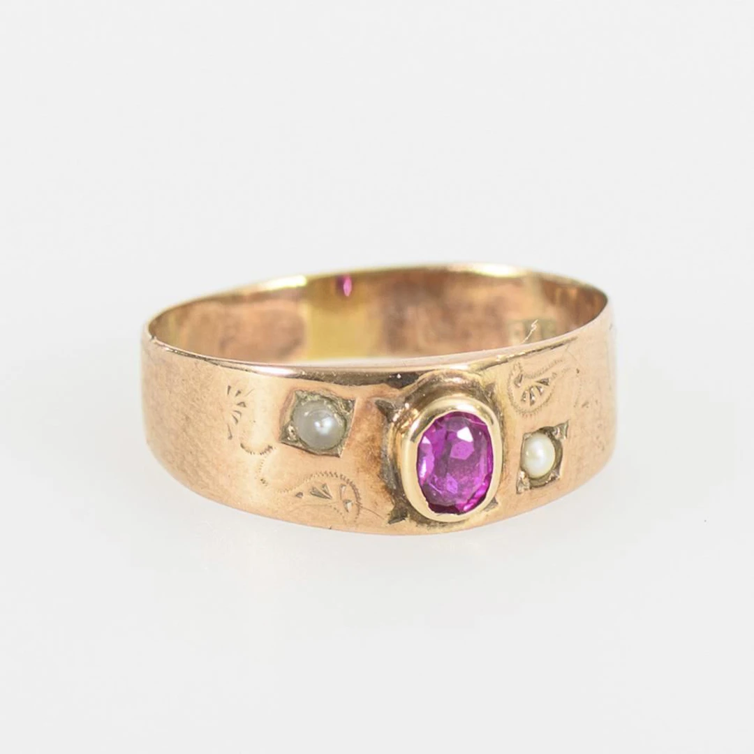 Very small ring with a red gemstone and seed pearls.