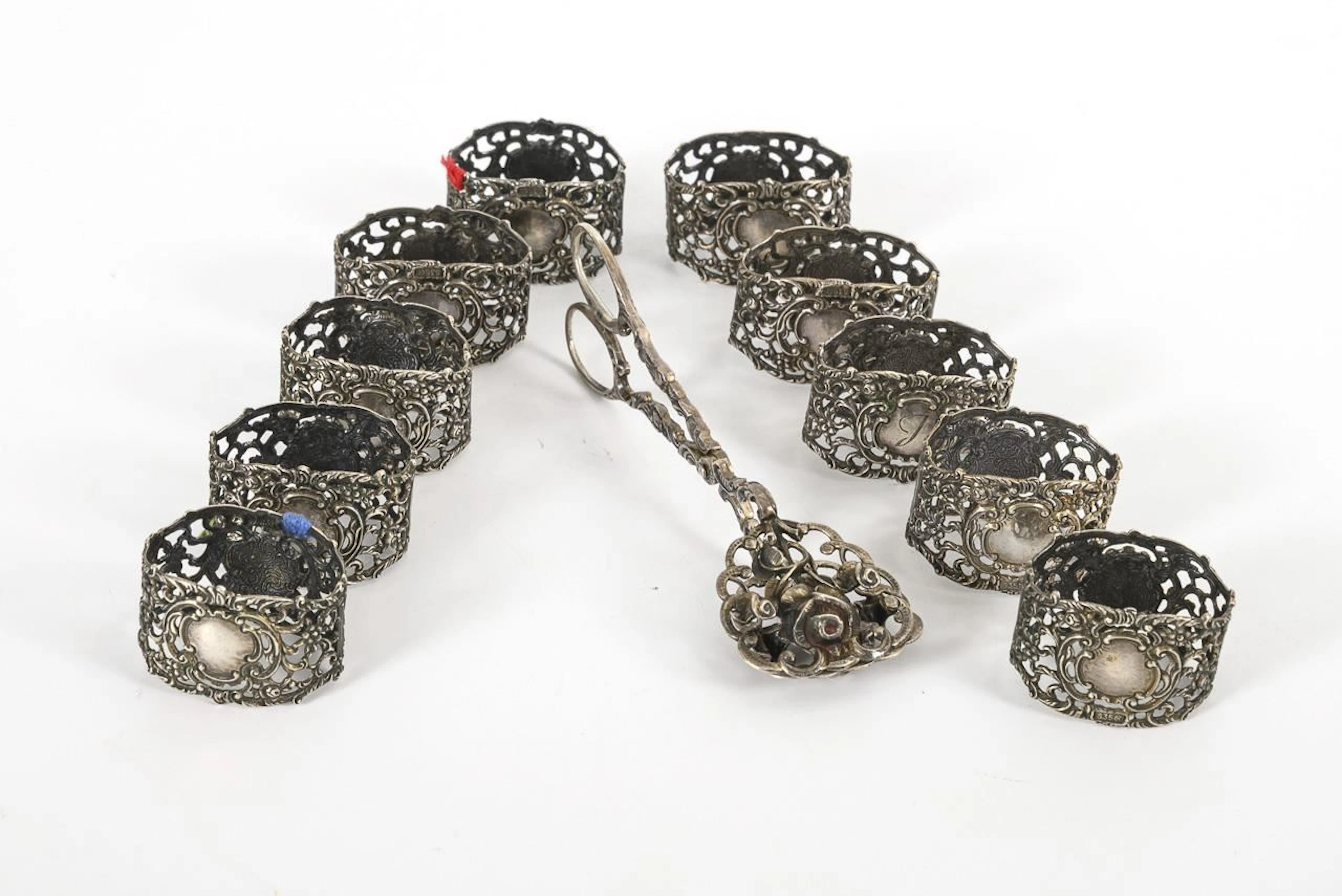 Silver pastry tongs and 10 napkin rings.