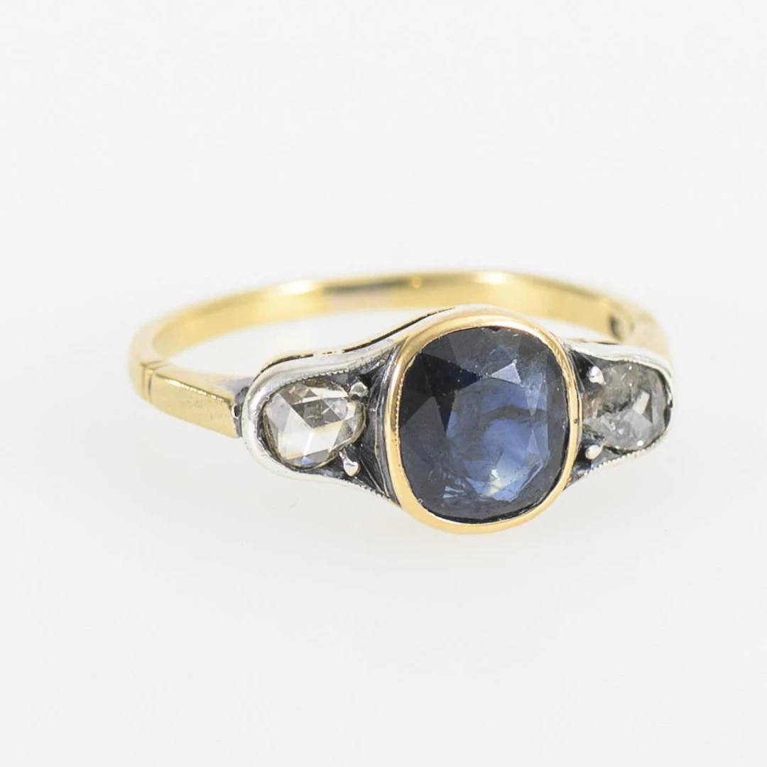 Ring with a blue gemstone, likely a sapphire, and diamond roses.