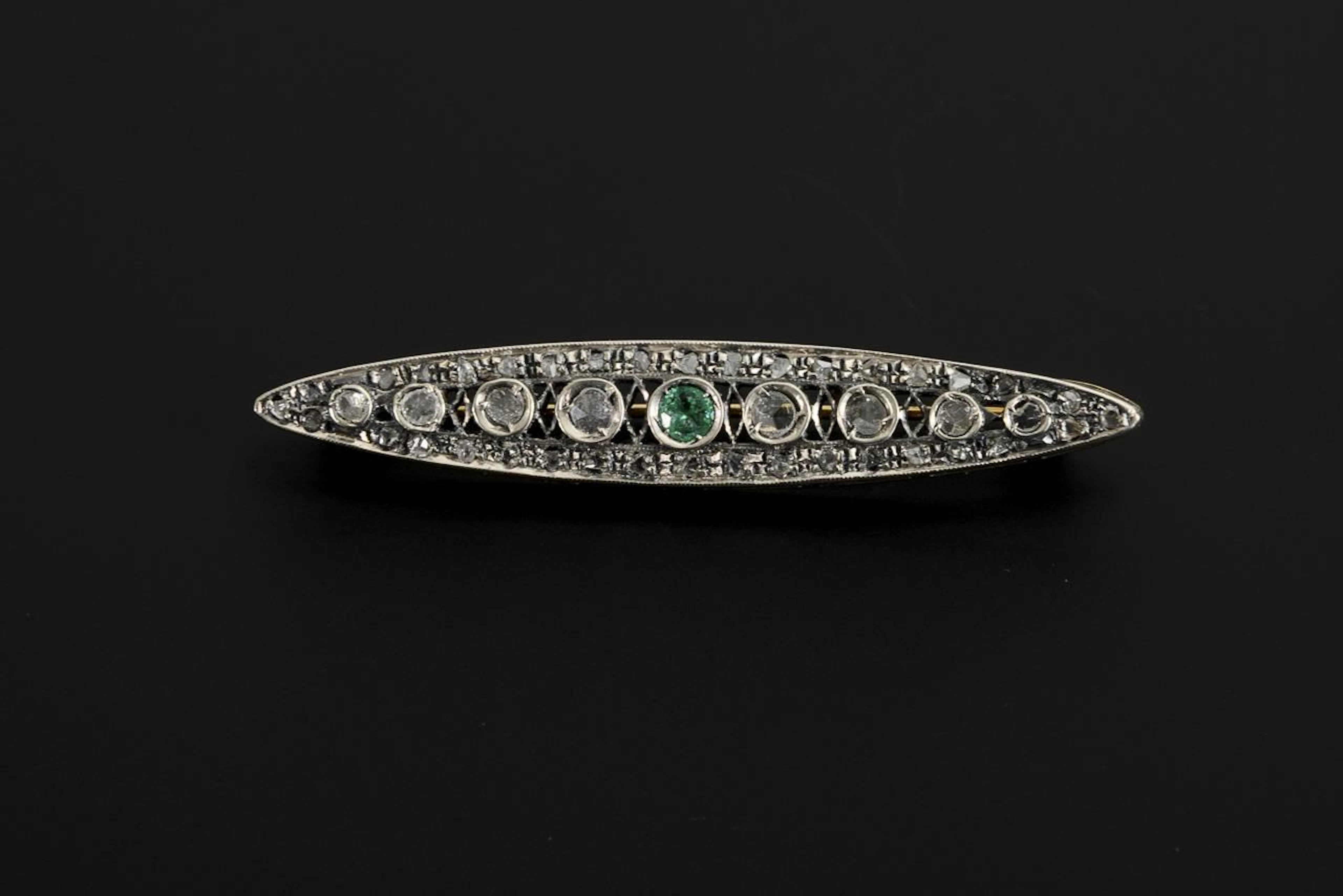 Art Deco-style brooch with diamond chips and a green gemstone, likely