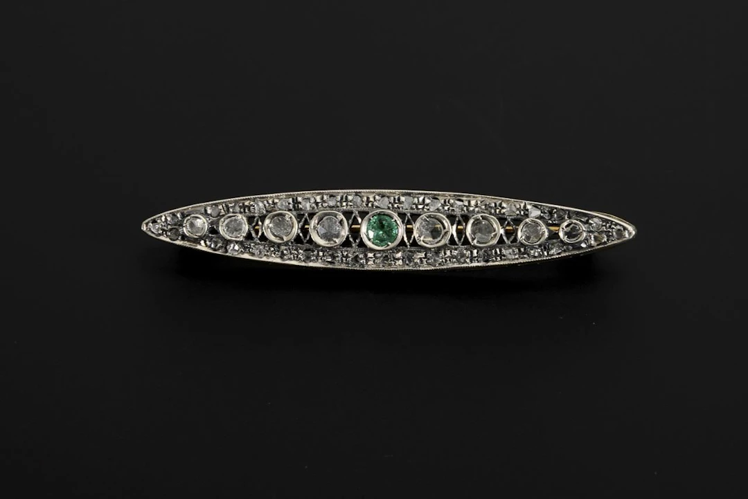 Art Deco-style brooch with diamond chips and a green gemstone, likely