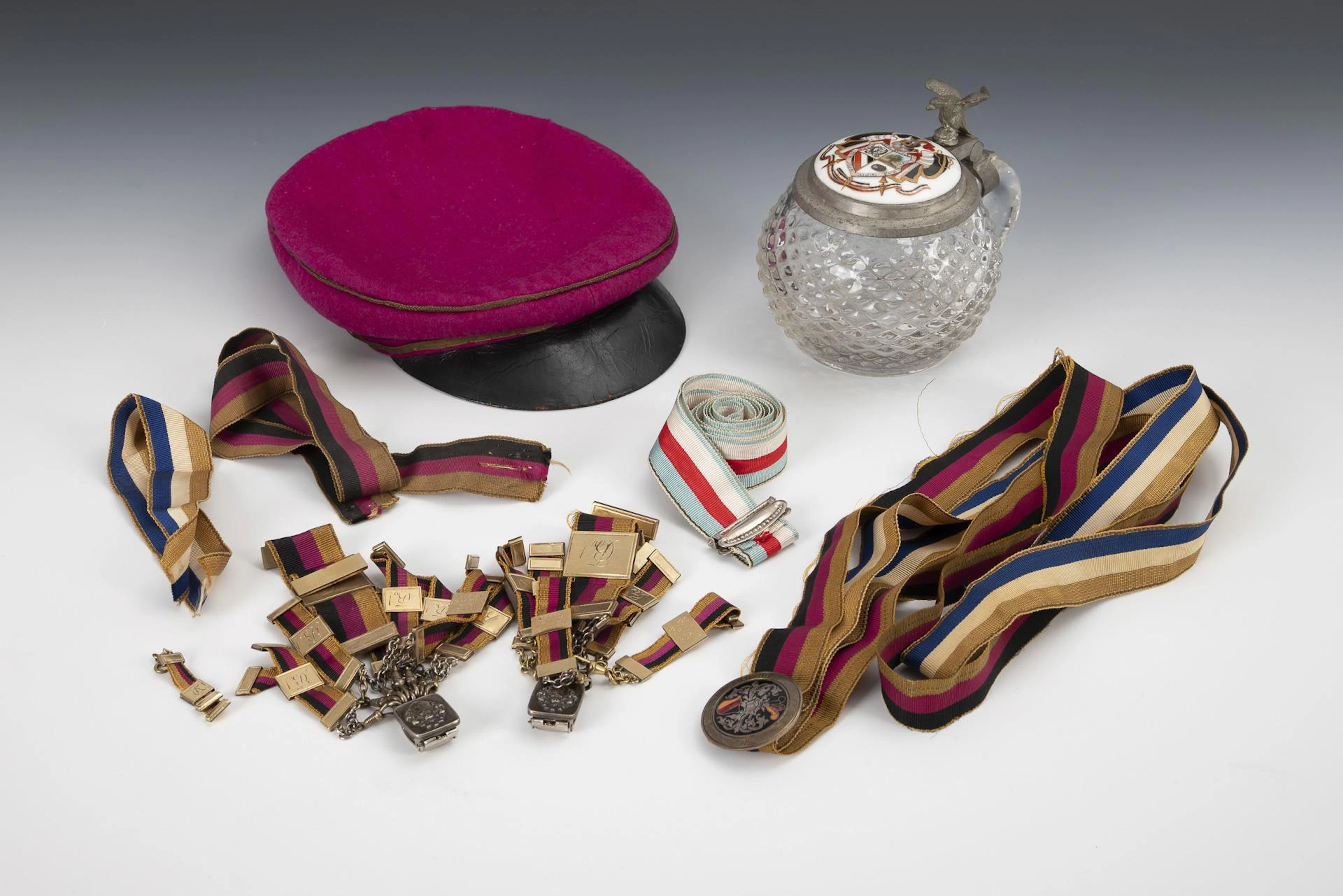 Collection of student items: Beer mug, cap, beer tail and ribbons.