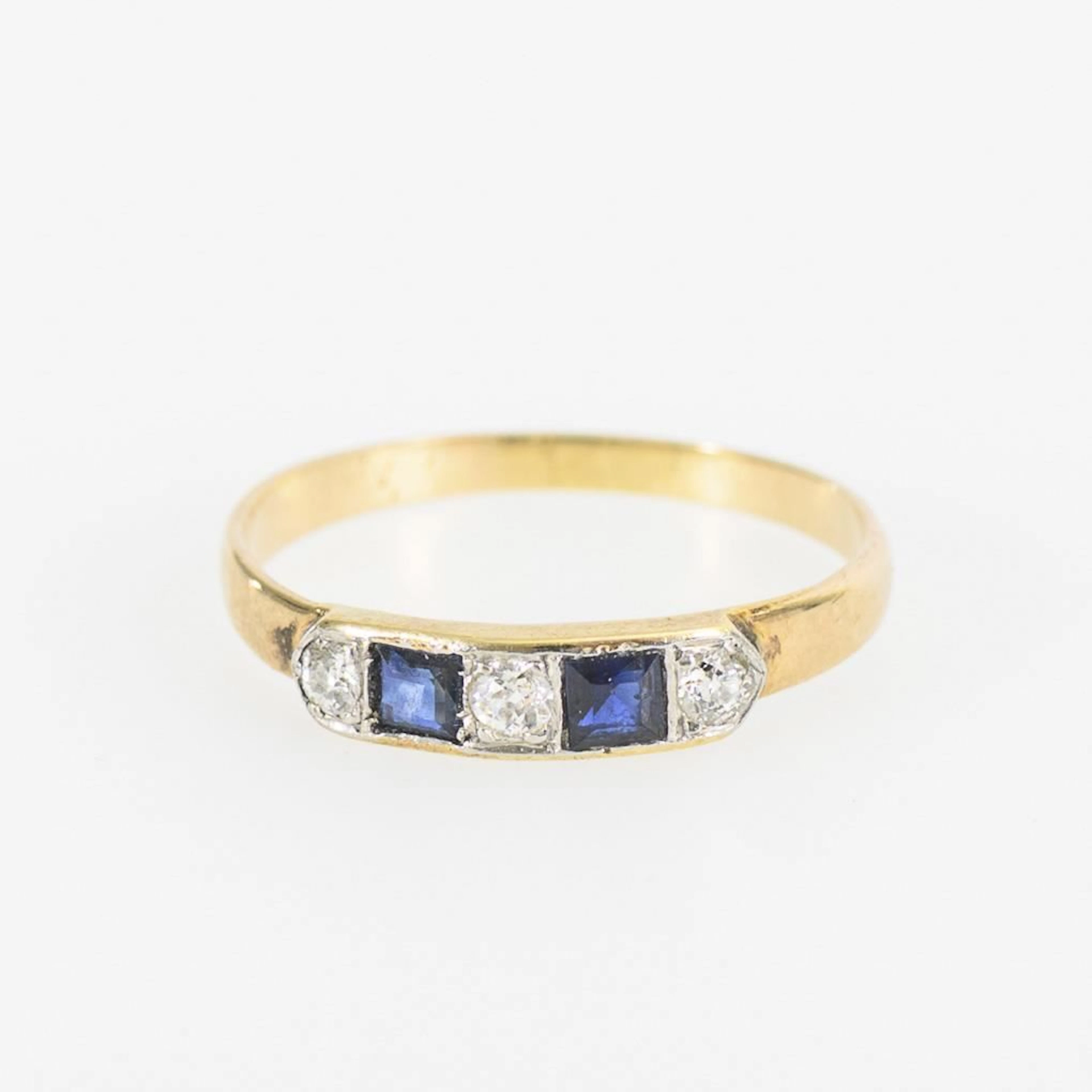Ring set with square-cut blue gemstones—likely sapphires—and old-cut diamonds.