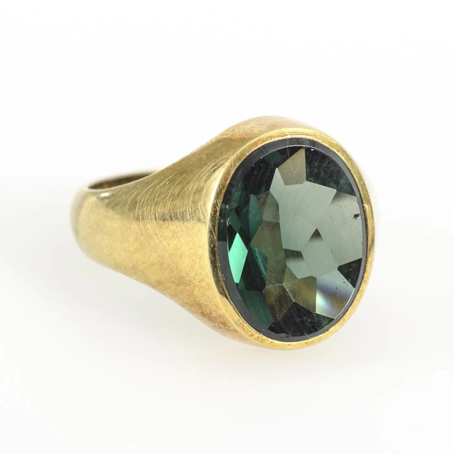 Heavy ring with a green gemstone or synthetic stone.