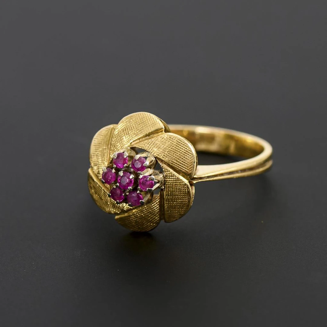 Modern flower-shaped ring with red gemstones, likely rubies.