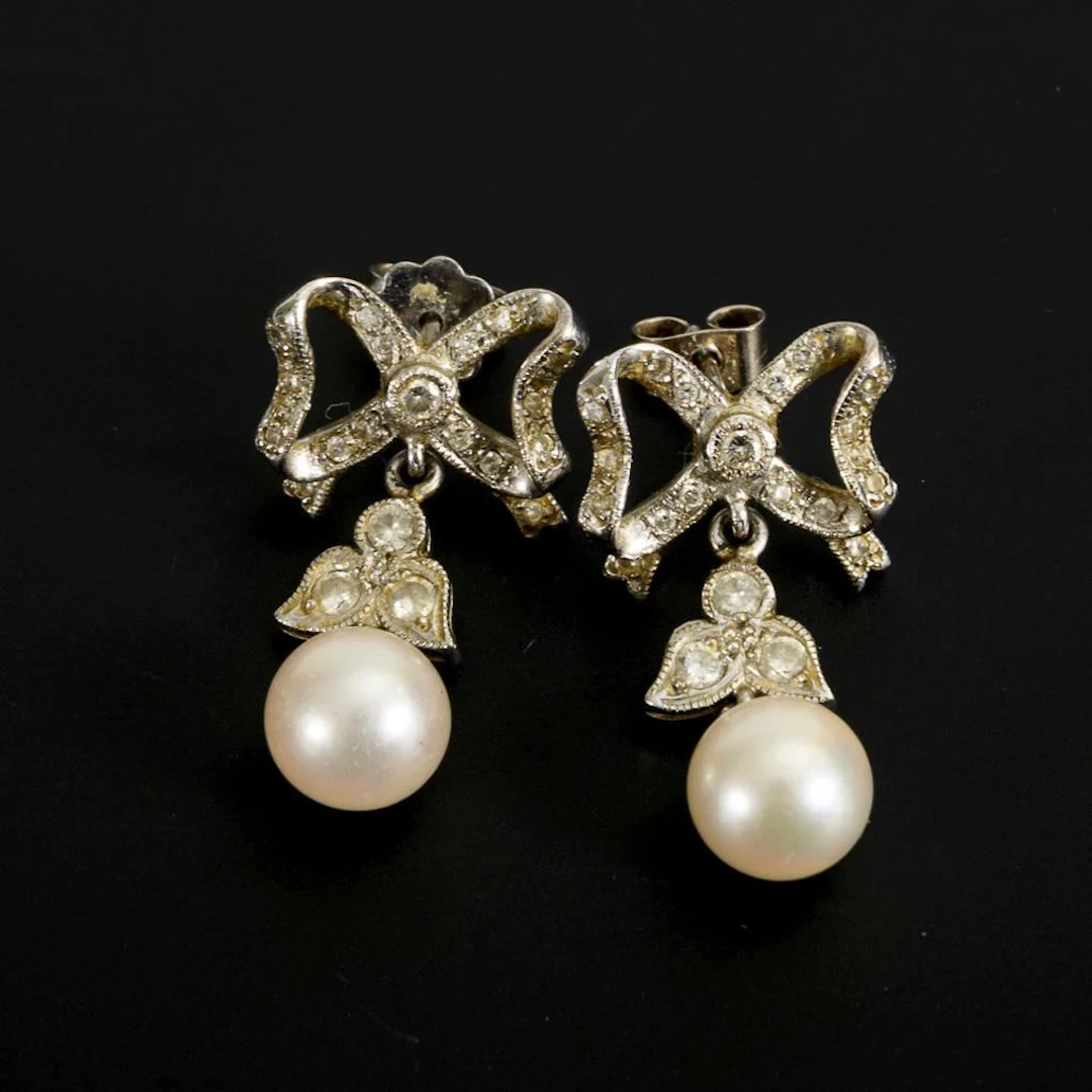 Pearl stud earrings with bow motif.