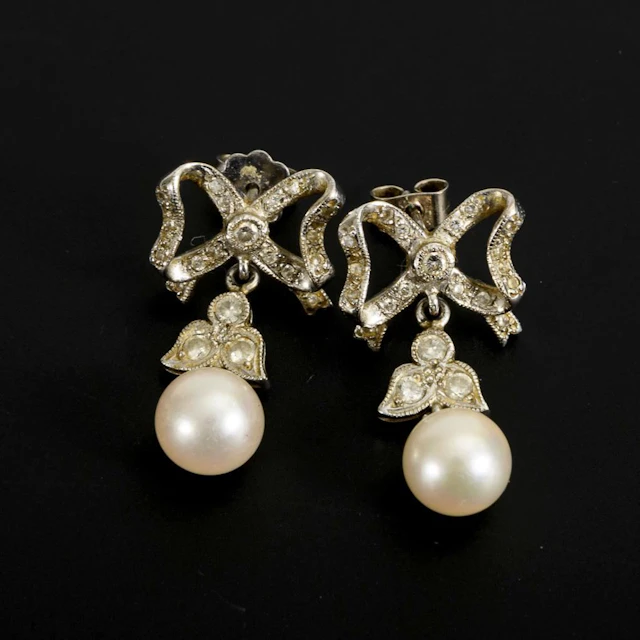 Pearl stud earrings with bow motif.